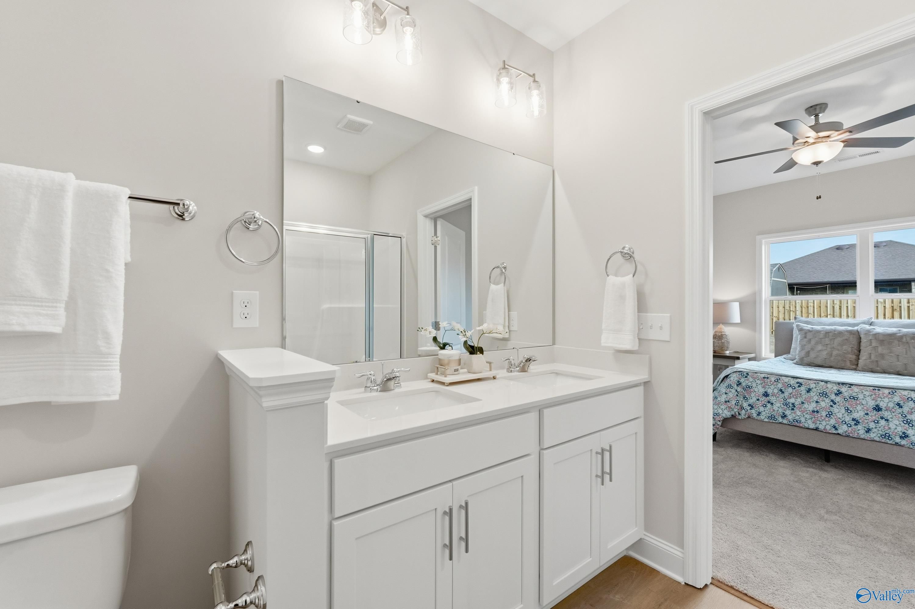Modern master bathroom featuring double vanity, frameless shower, and bedroom view in Davidson Homes The Asheville, Toney, AL