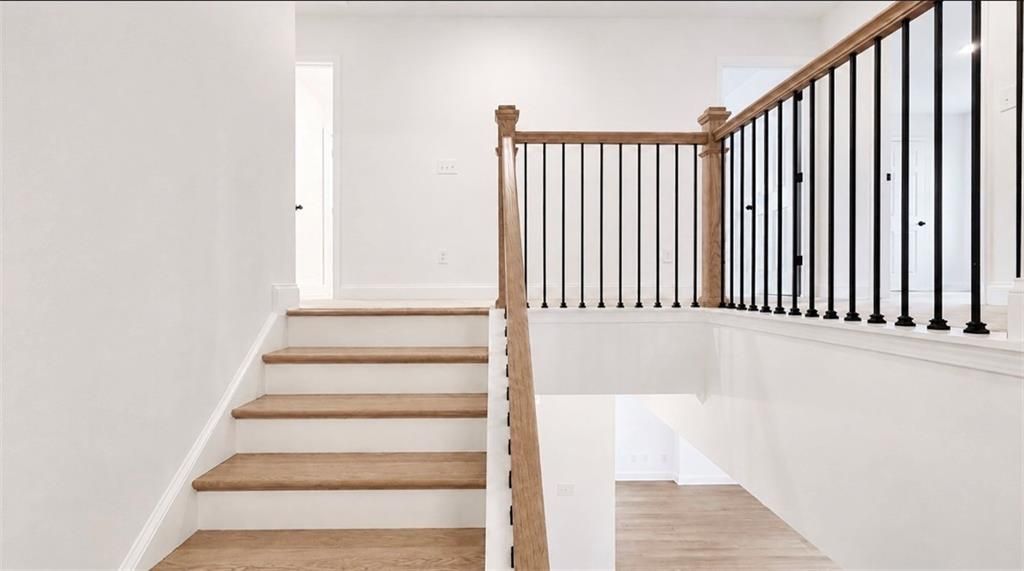 Hardwood staircase with black metal balusters in The Hickory C floor plan at Wehunt Meadows, Hoschton, Georgia.