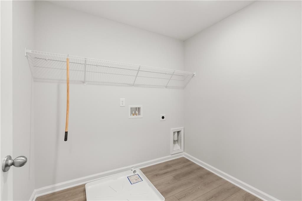 Laundry room with wire shelving and wood-look flooring in The Burton A home by Davidson Homes at The Bluffs, Canton, GA.