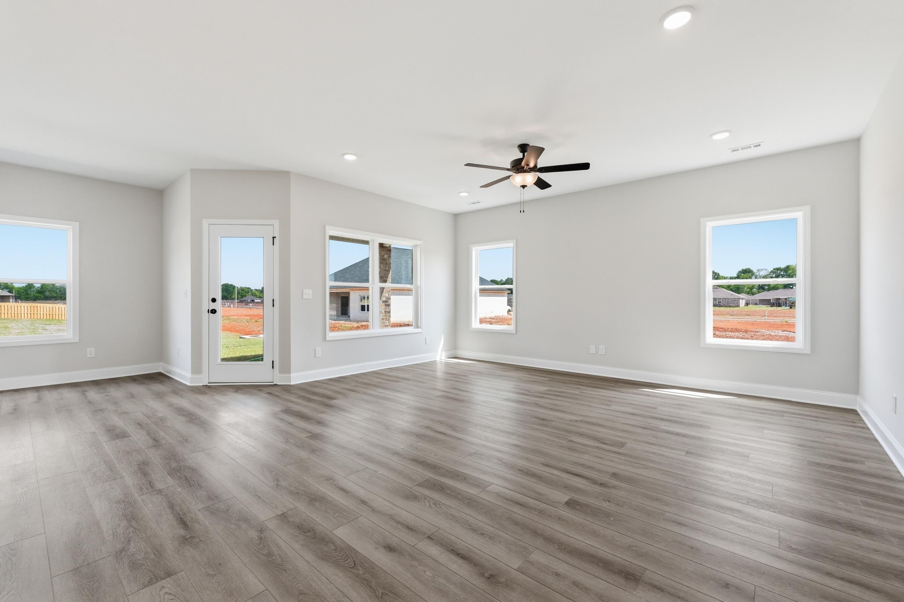 Bright, open-concept living area in The Glen A floor plan featuring wood-style flooring and large windows.