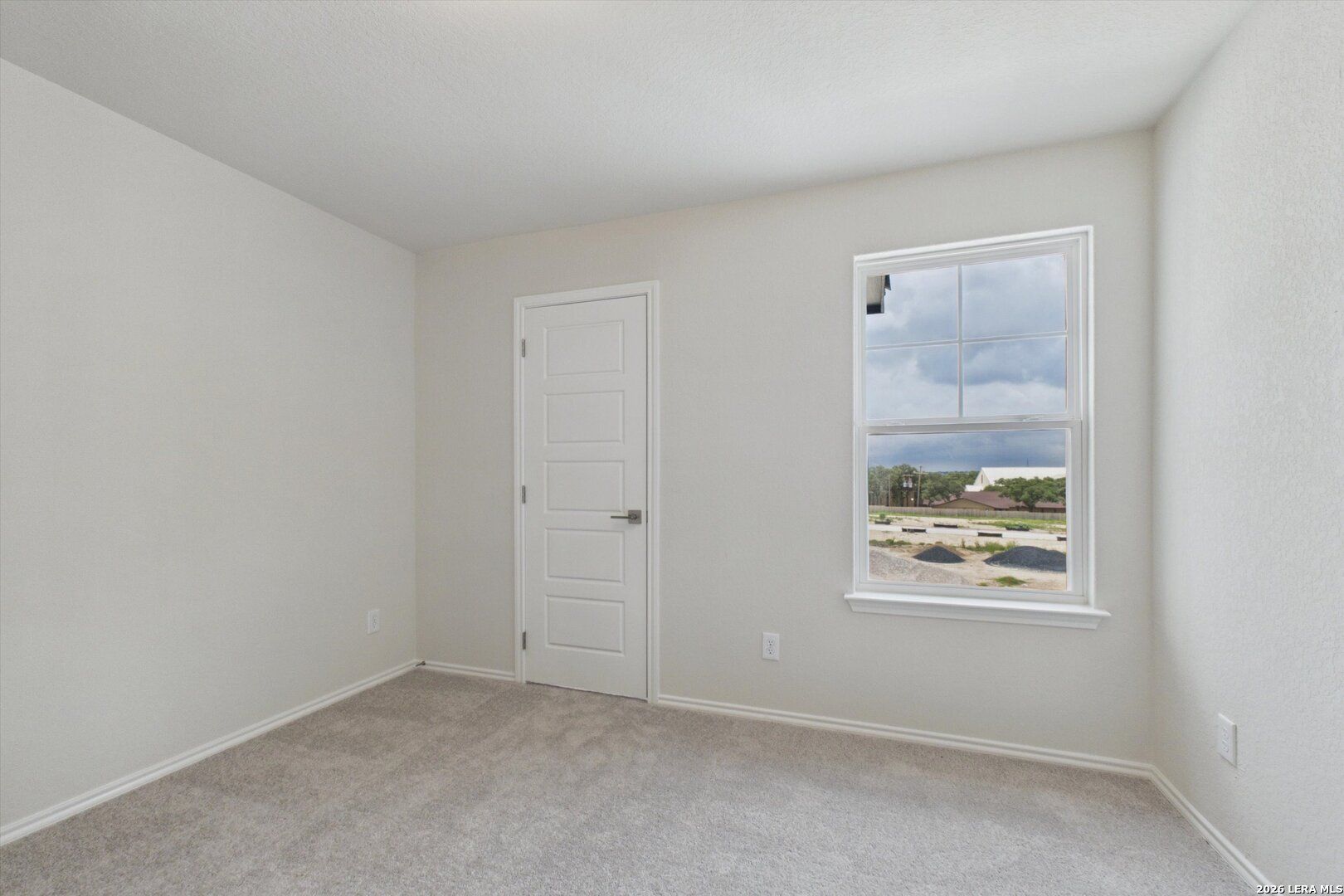 Bright bedroom with neutral carpet and window view in The Charlotte B floor plan at Meadows at Oak Creek, San Antonio.
