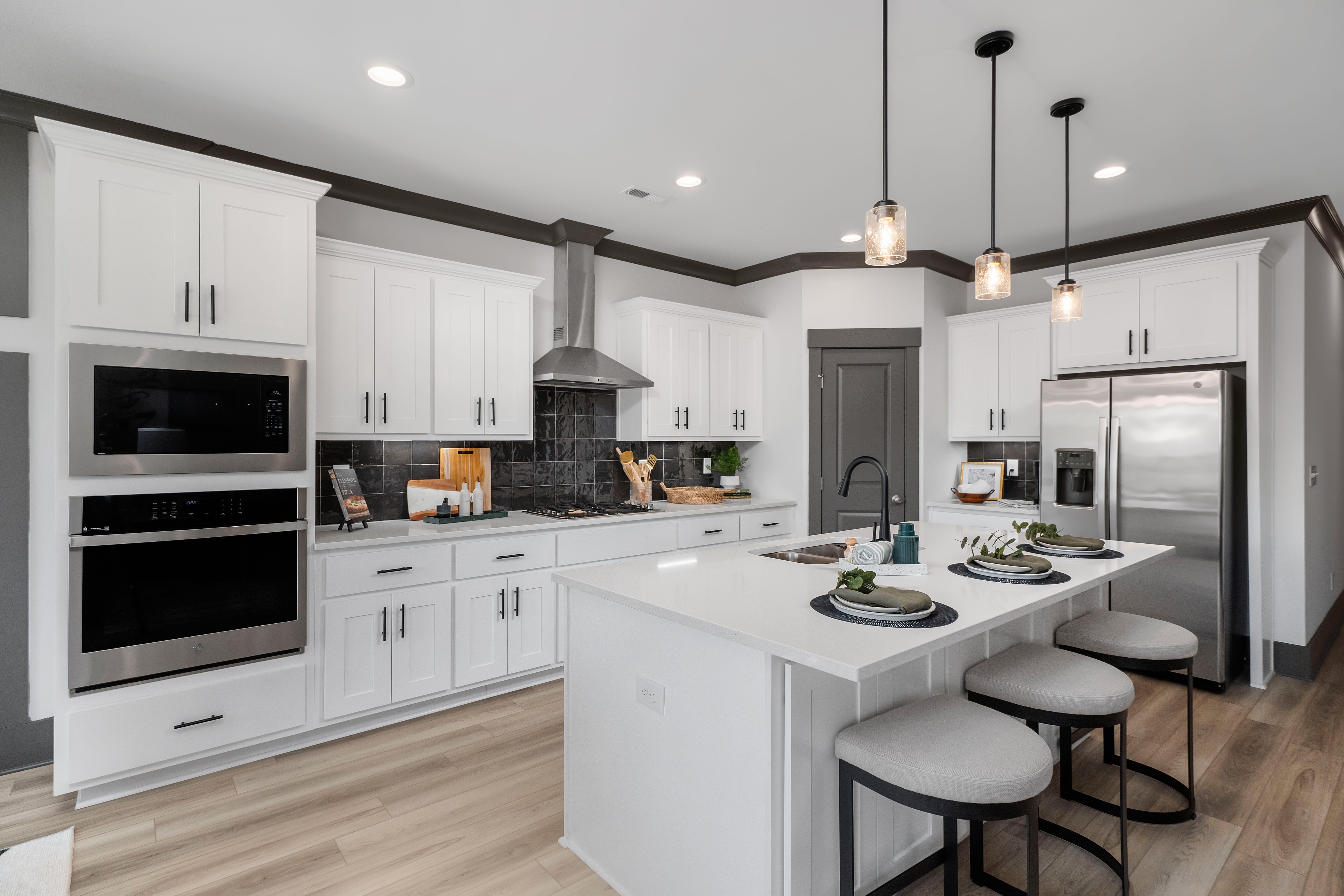 Modern kitchen at Barnett's Crossing in Madison Alabama with white cabinets stainless steel appliances and island seating