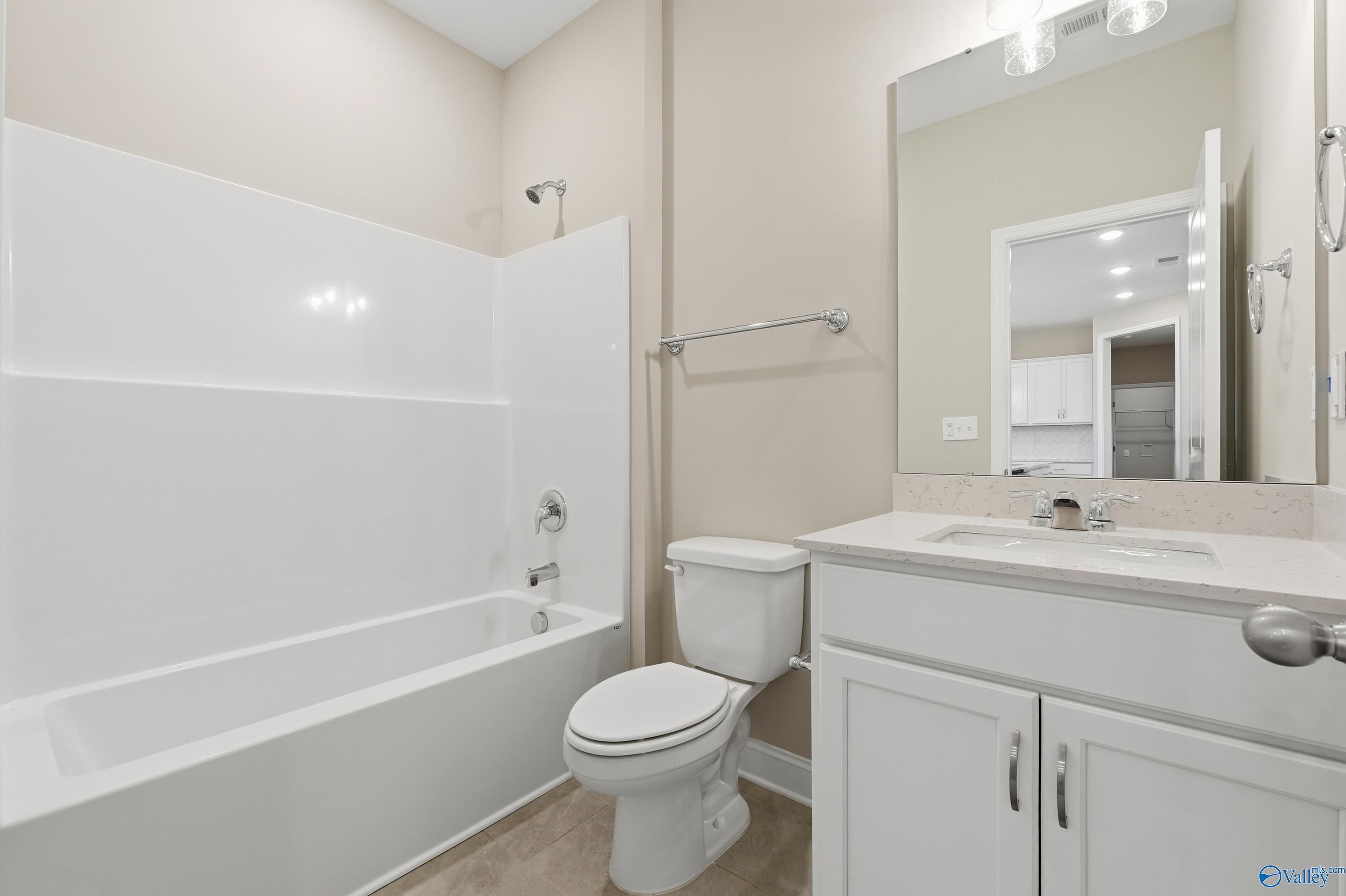 Modern bathroom with white bathtub, shower combo, vanity, mirror, and toilet in Davidson Homes The Lanier, Meridianville, Alabama
