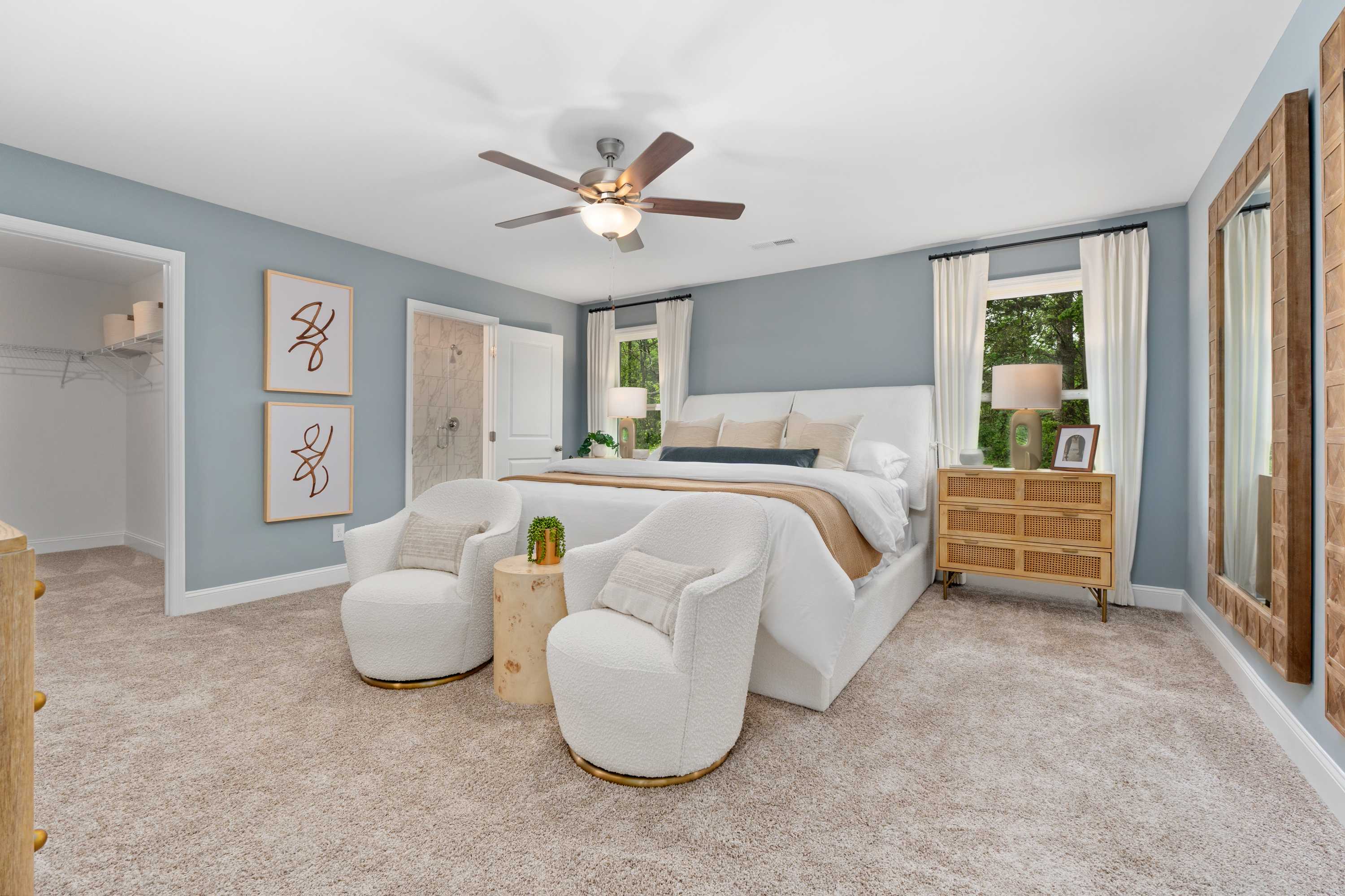 Spacious master bedroom in Pavilion Huntsville AL with king bed, white accent chairs, wooden nightstands, ceiling fan, and blue walls