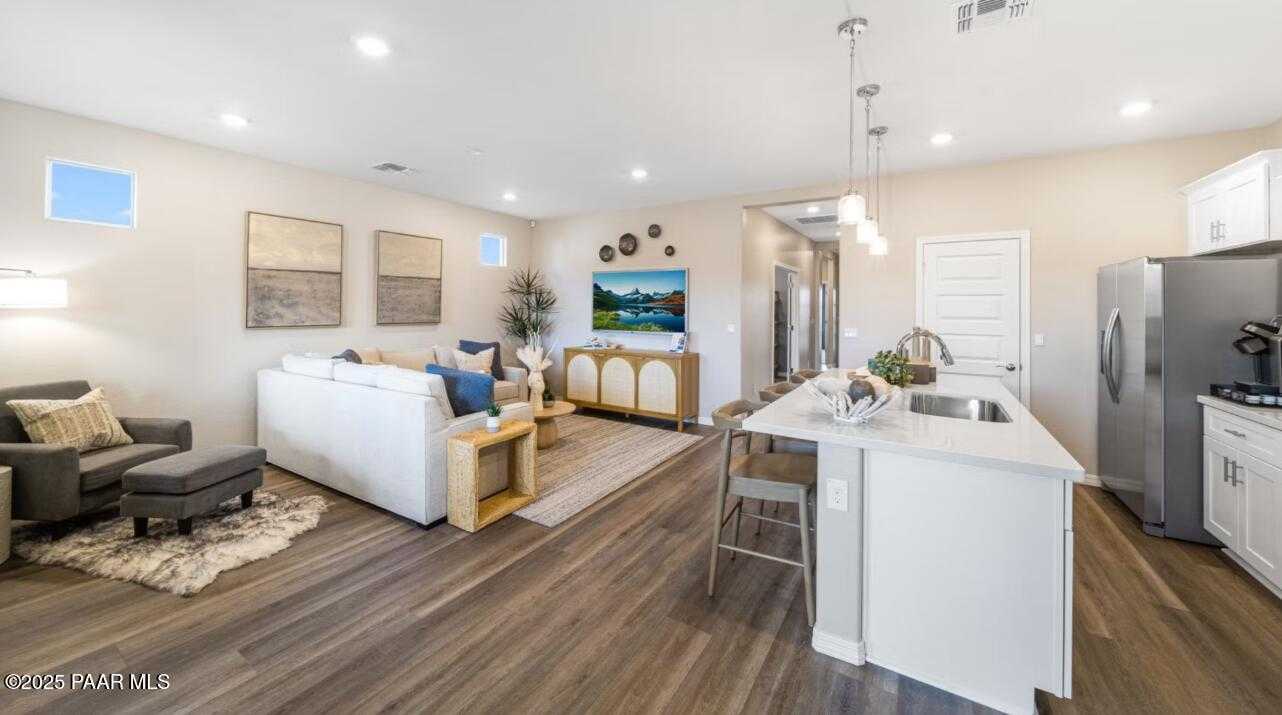 Open-concept living room and kitchen with white island, stainless appliances, hardwood floors in Davidson Homes The Newport C, Prescott AZ