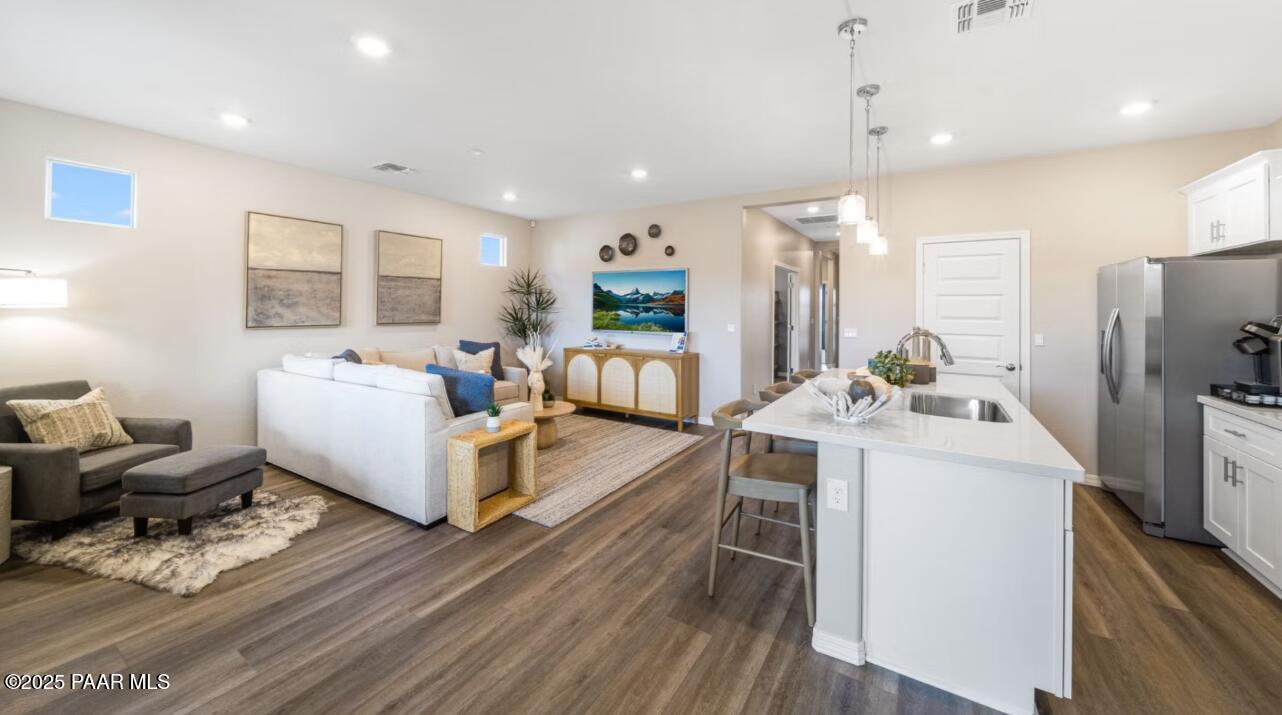 Open-concept living room and kitchen with white island, stainless appliances, and hardwood floors in Davidson Homes The Newport C, Prescott, Arizona