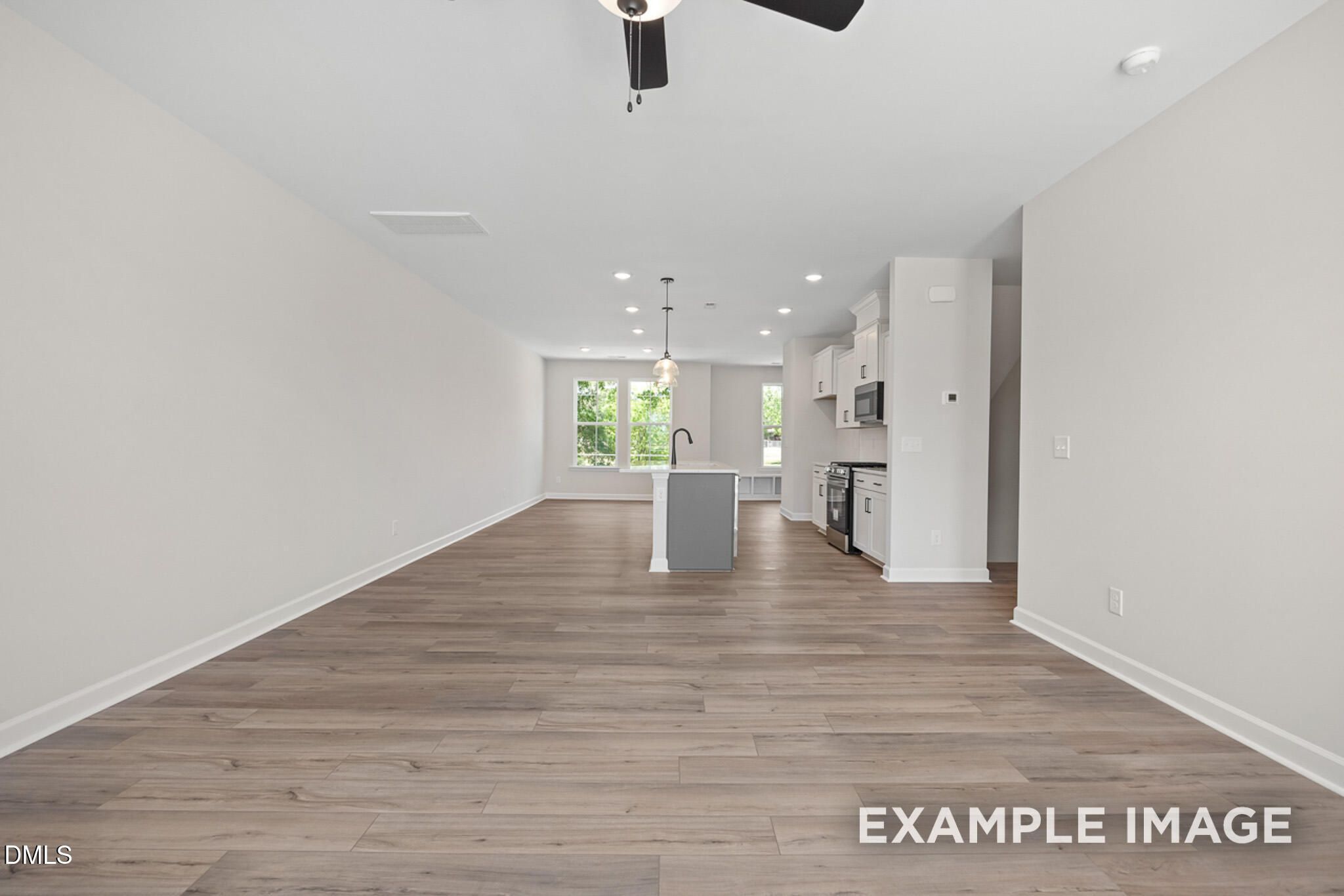 Open-concept kitchen and living area with wood-style flooring in The Mitchell floor plan at Camden Park, Knightdale, NC.