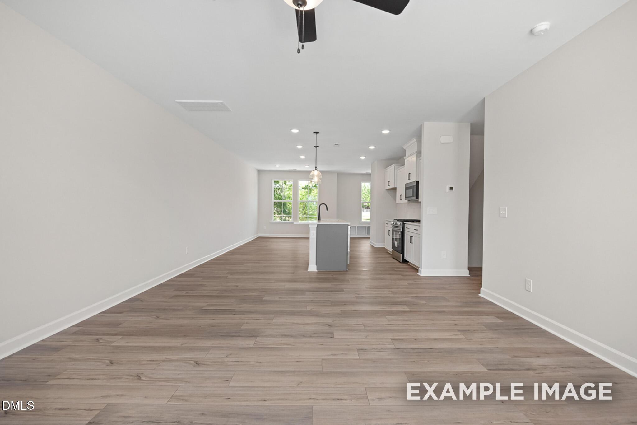 Open-concept kitchen and living area with wood-style flooring in The Mitchell floor plan at Camden Park, Knightdale, NC.