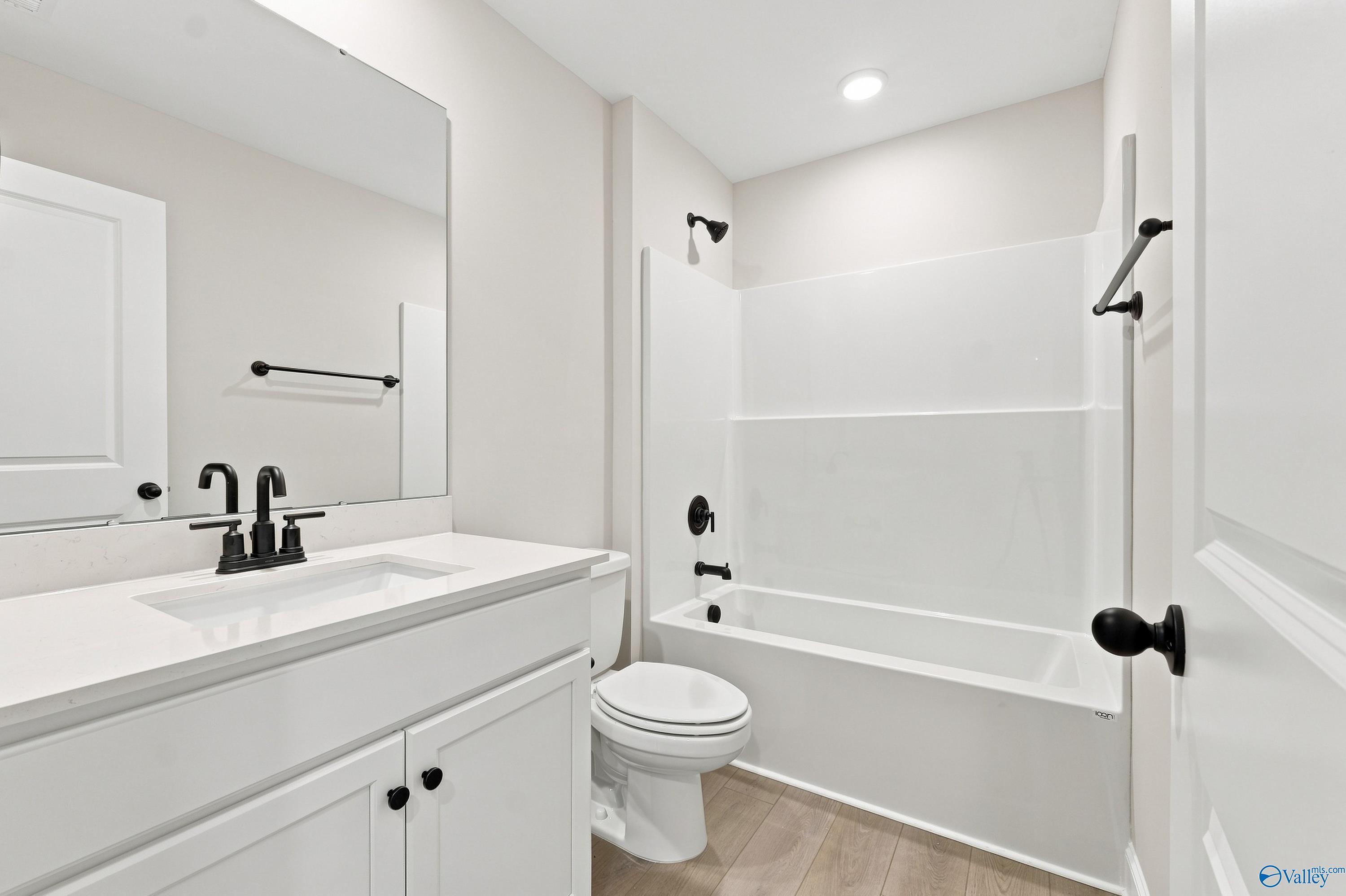 Modern bathroom with white vanity, tub-shower combo, and matte black fixtures in The Rockford B home in Kendall Downs, Toney.