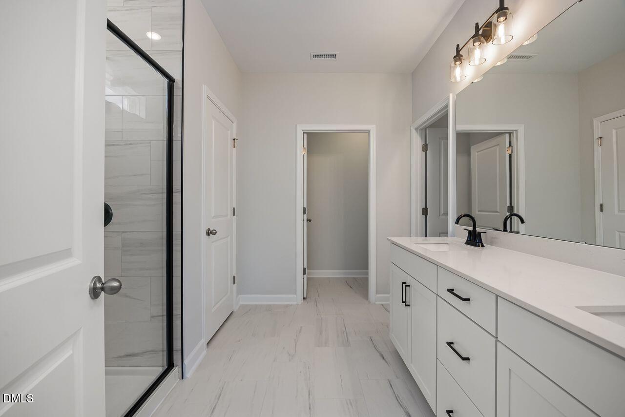 Modern primary bathroom with double vanity, walk-in shower, and marble-look tile in Davidson Homes The Birch II A floor plan.