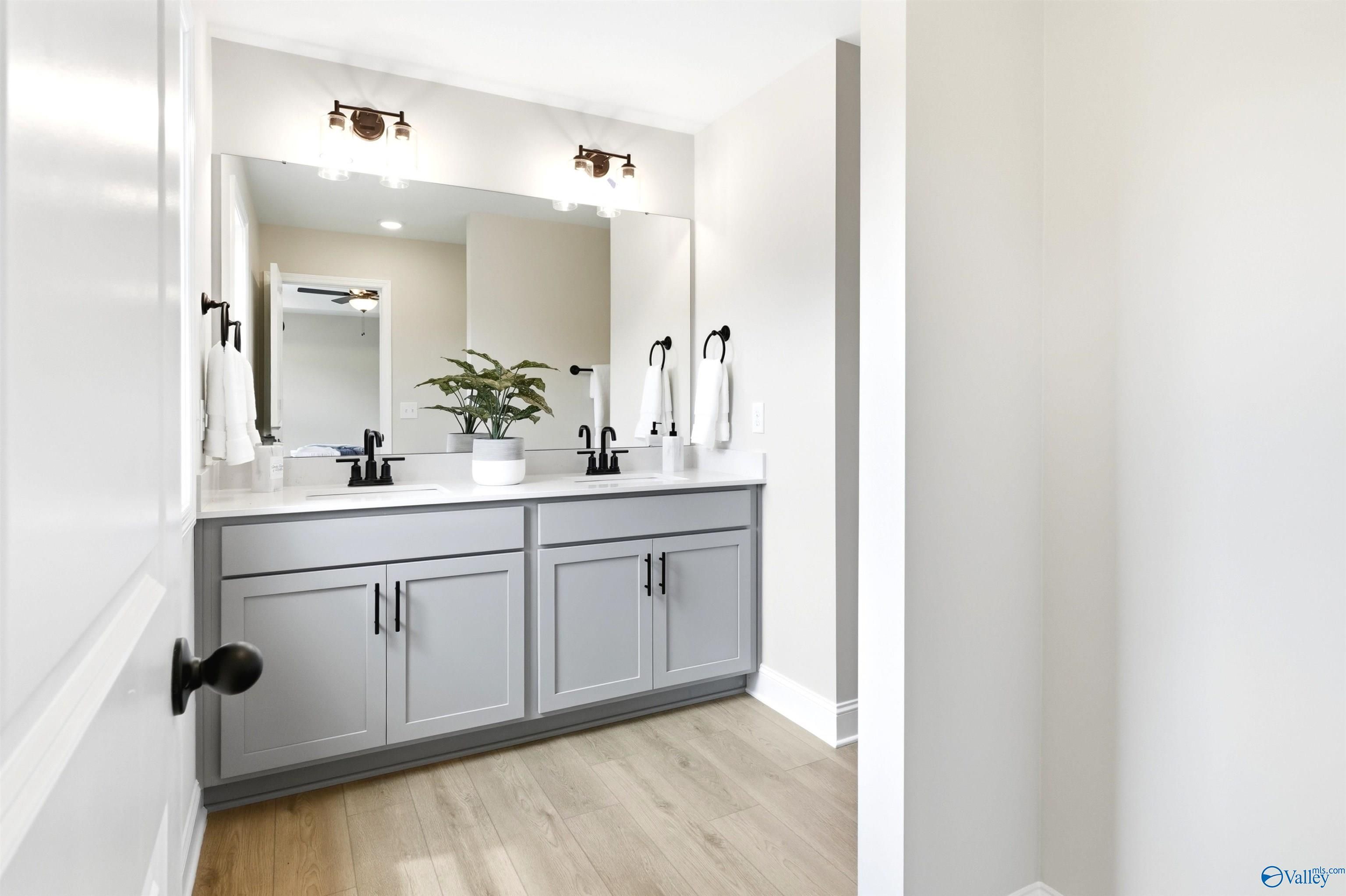 Dual vanity bathroom with gray cabinets, black fixtures, and large mirror in The Russell A floor plan, Huntsville, Alabama