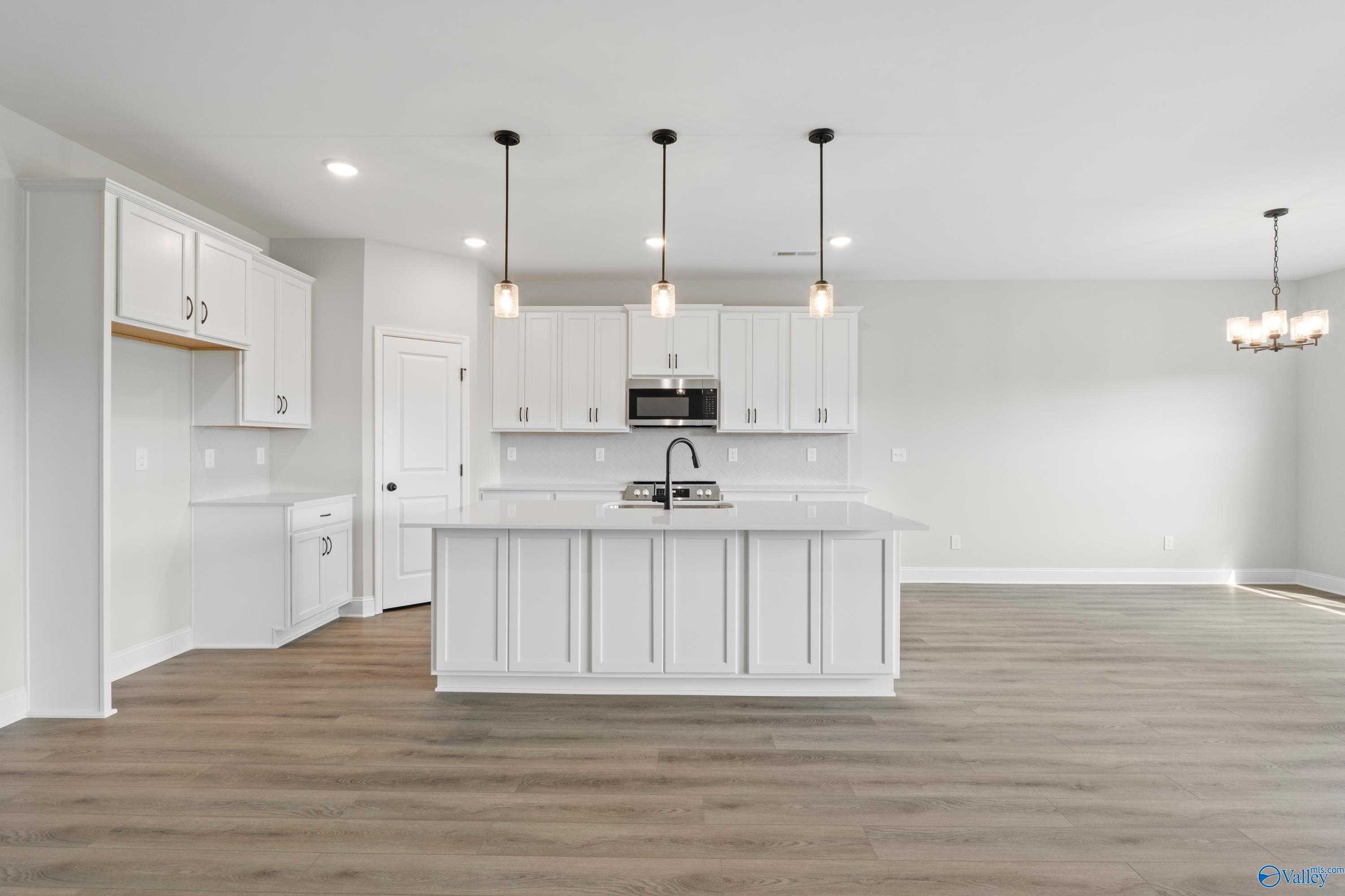 Modern white shaker kitchen with quartz island, stainless appliances, and pendant lights in Davidson Homes The Rockford, Toney, Alabama