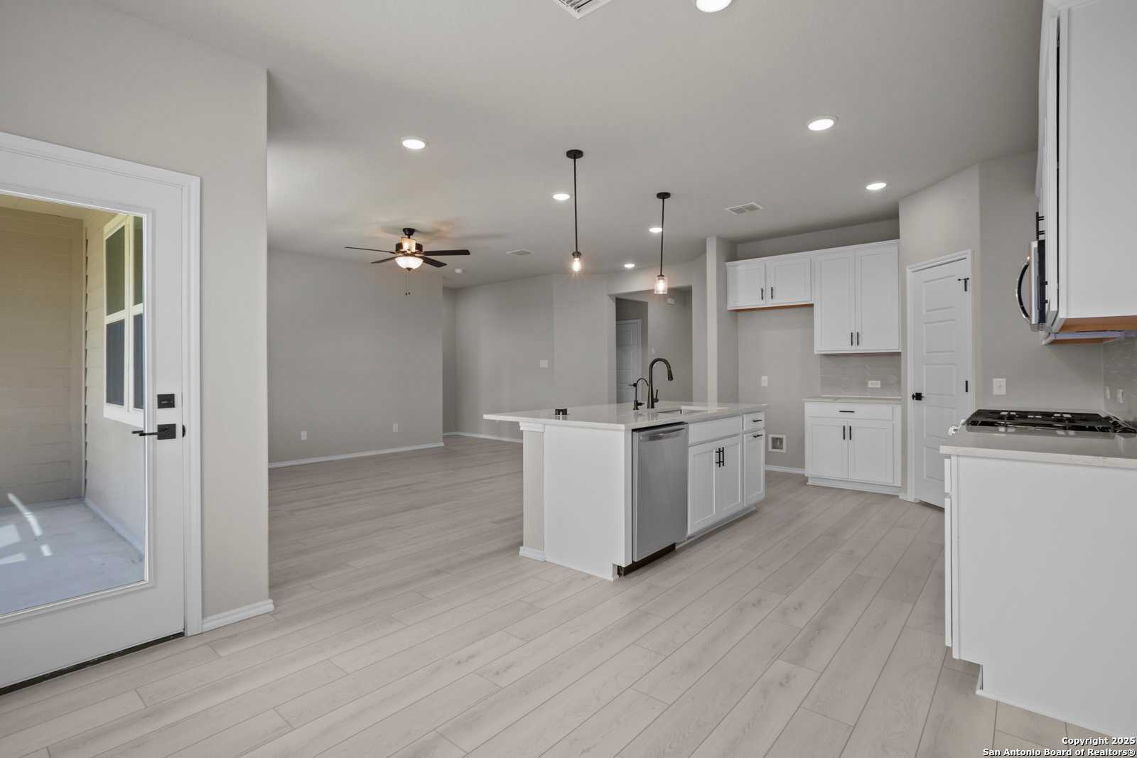 Modern open-concept kitchen with white shaker cabinets, quartz island, stainless sink in The Asheville E, Davidson Homes, Converse, TX