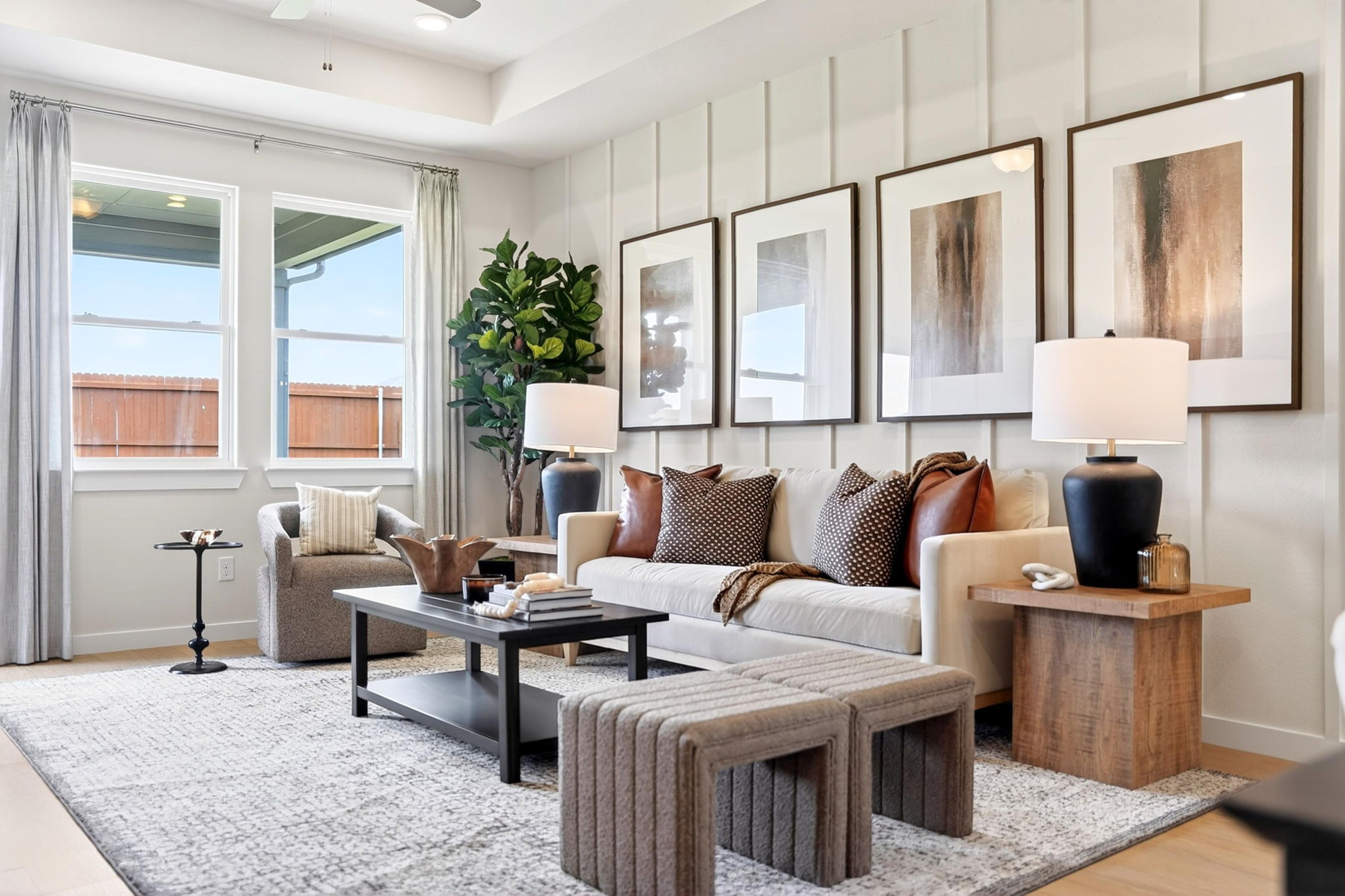 Spacious living room in Heartland Texas by Davidson Homes featuring neutral shiplap walls, beige sofa, abstract art, large windows