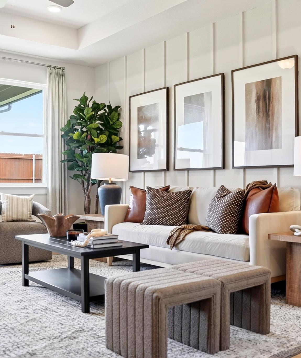 Spacious living room in Heartland Texas by Davidson Homes featuring neutral shiplap walls, beige sofa, abstract art, large windows