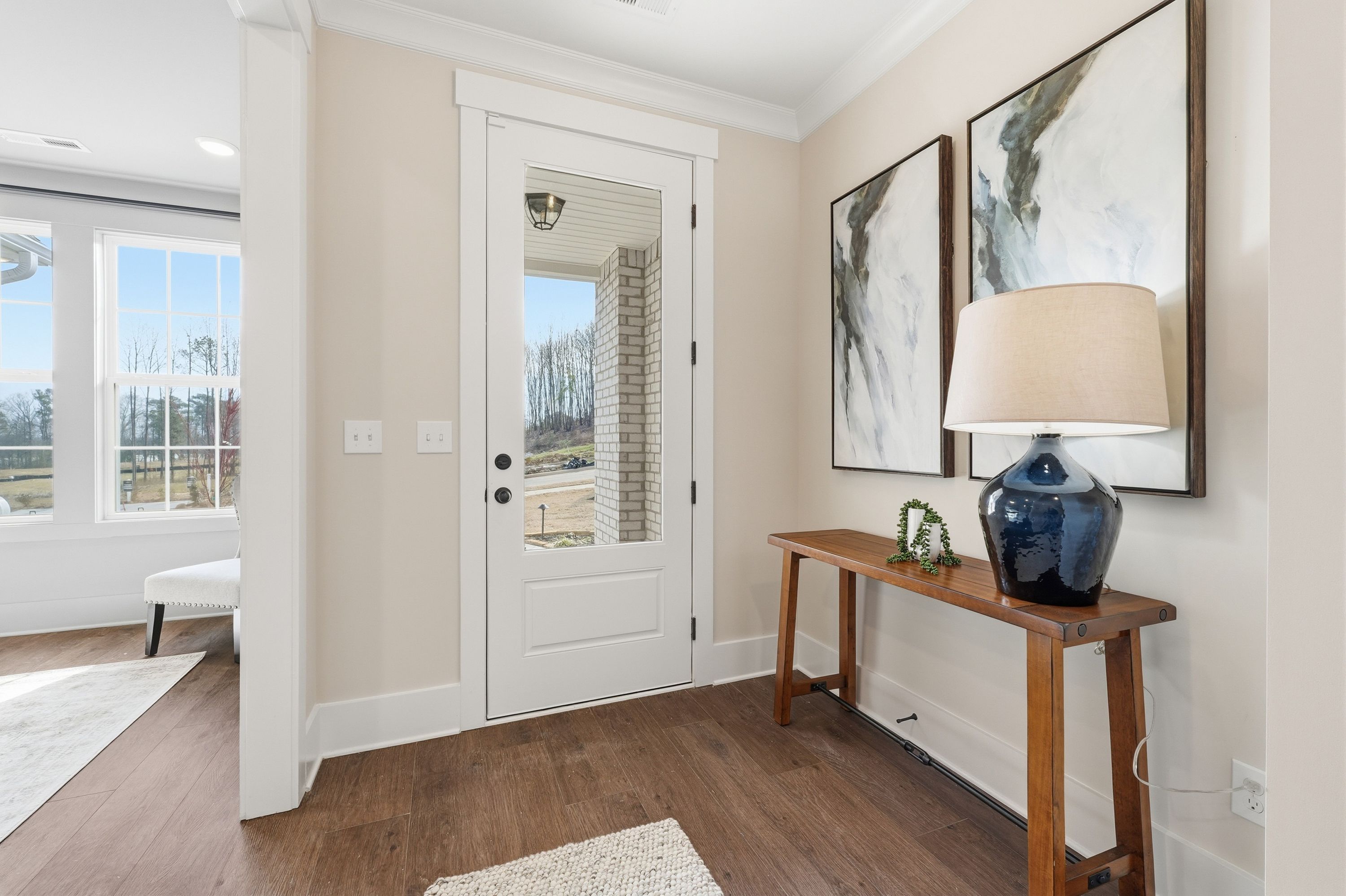 Spacious entry foyer at Noble Ridge in Cullman Alabama with hardwood floors white glass door oak console table and abstract wall art