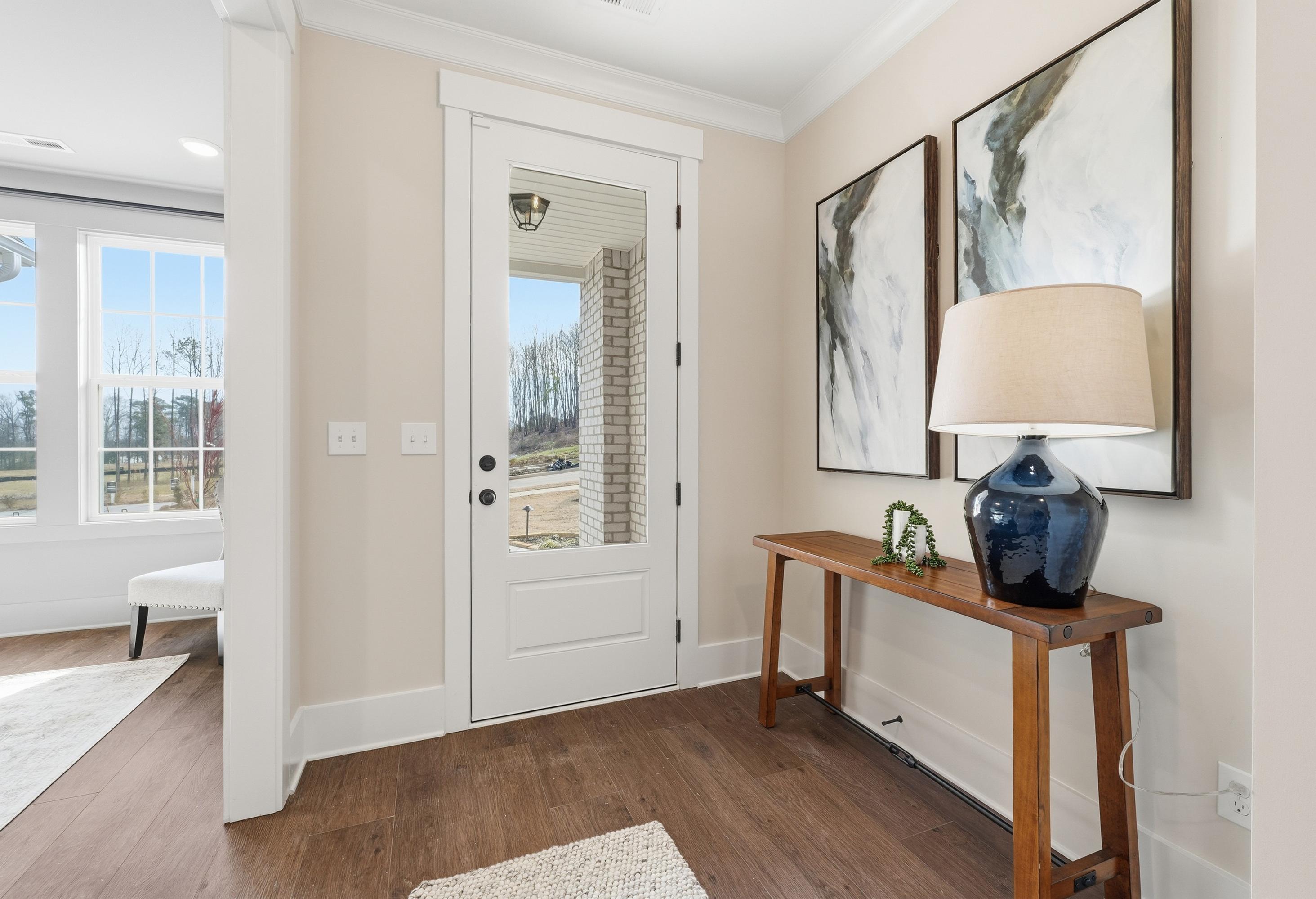 Bright entryway in The Hibiscus home design by Davidson Homes featuring a glass-paneled front door and wood flooring.