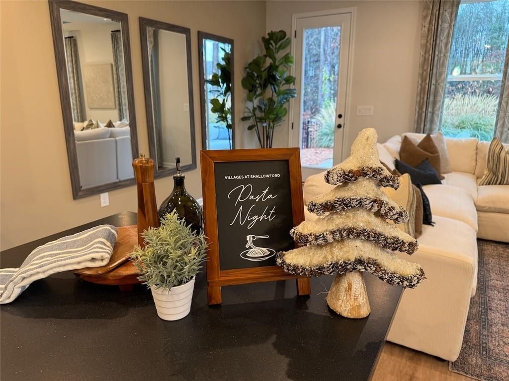 Cozy pasta night setup on dark wood console with chalkboard sign, utensils, plants beside beige sectional sofa in The Marion B living room, Kennesaw, GA