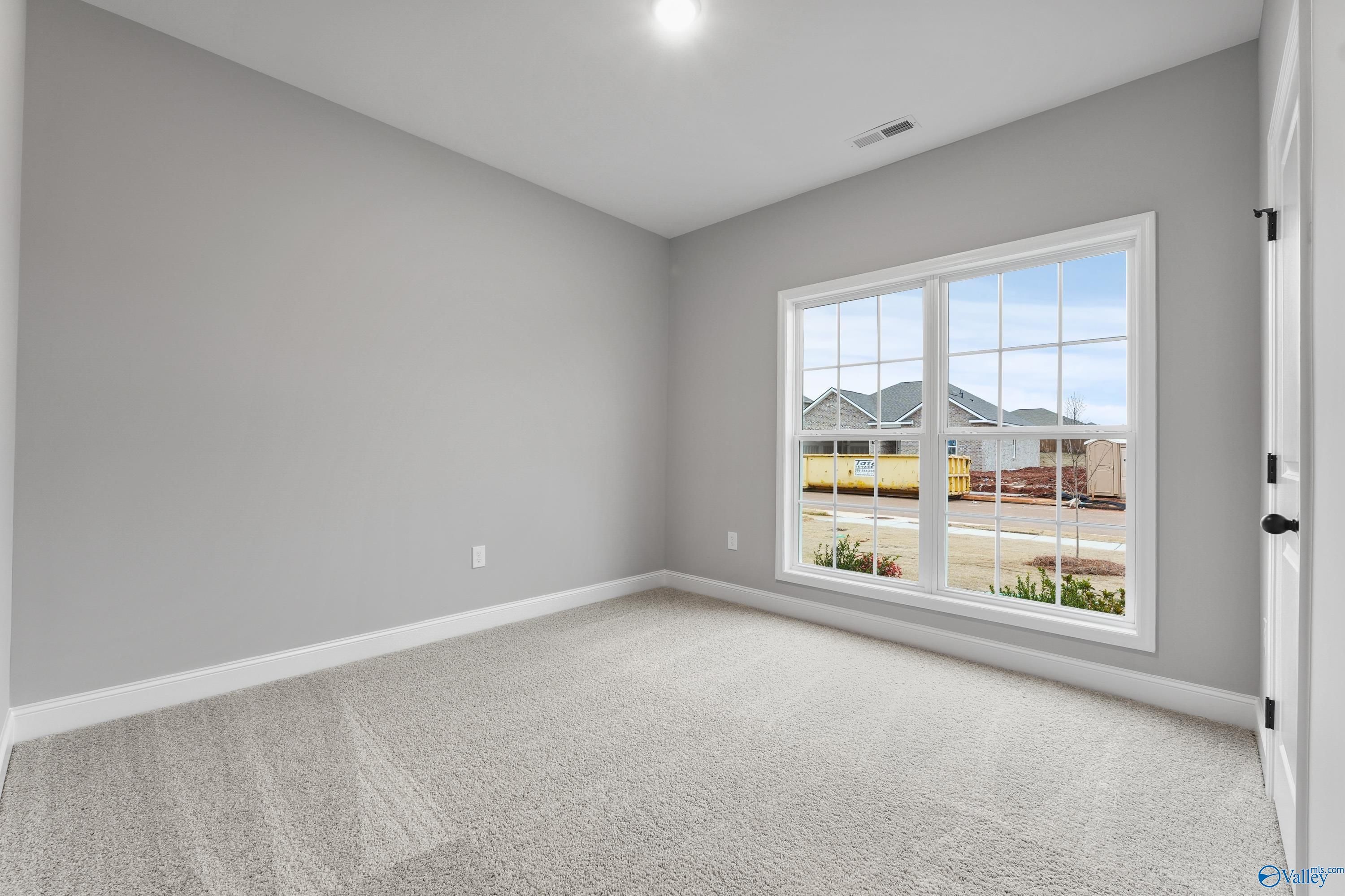Bright secondary bedroom with gray walls, carpet flooring, and large window overlooking neighborhood in Davidson Homes Asheville C, Meridianville AL