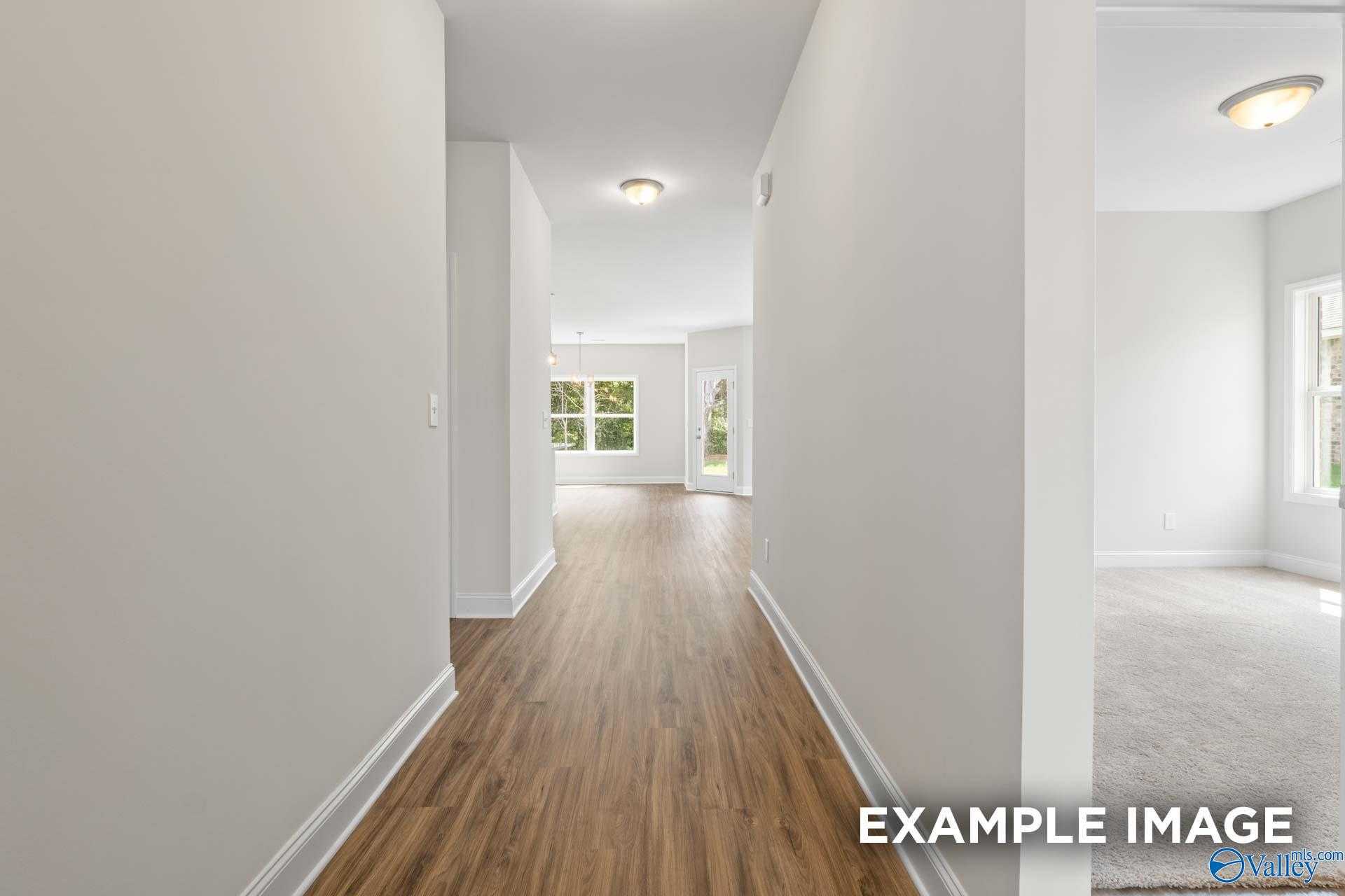 Bright hallway with hardwood floors, white walls, and glass back door in The Franklin home, Davidson Homes, Meridianville, Alabama