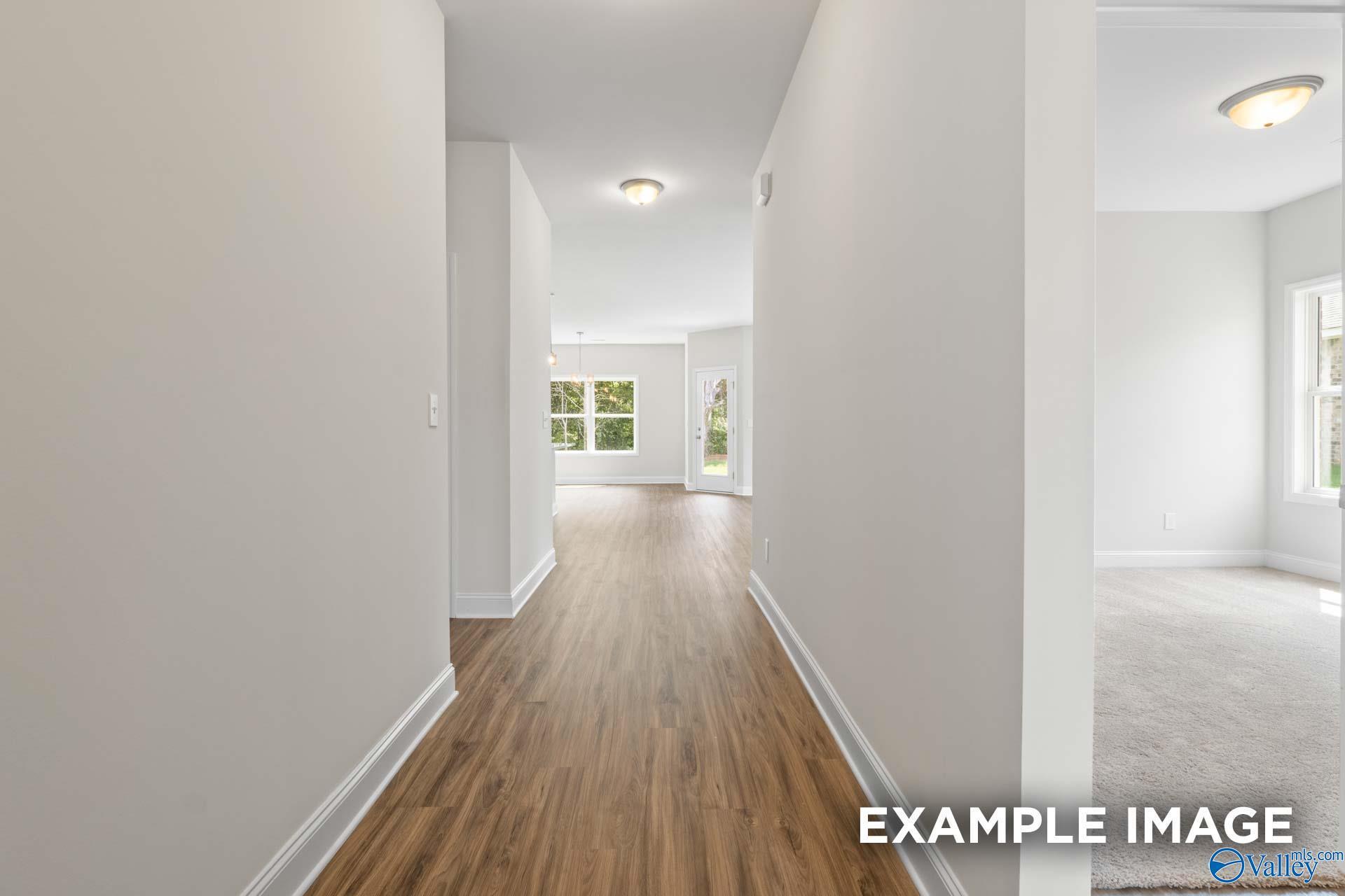 Bright hallway with hardwood floors, white walls, and glass back door in The Franklin home, Davidson Homes, Meridianville, Alabama