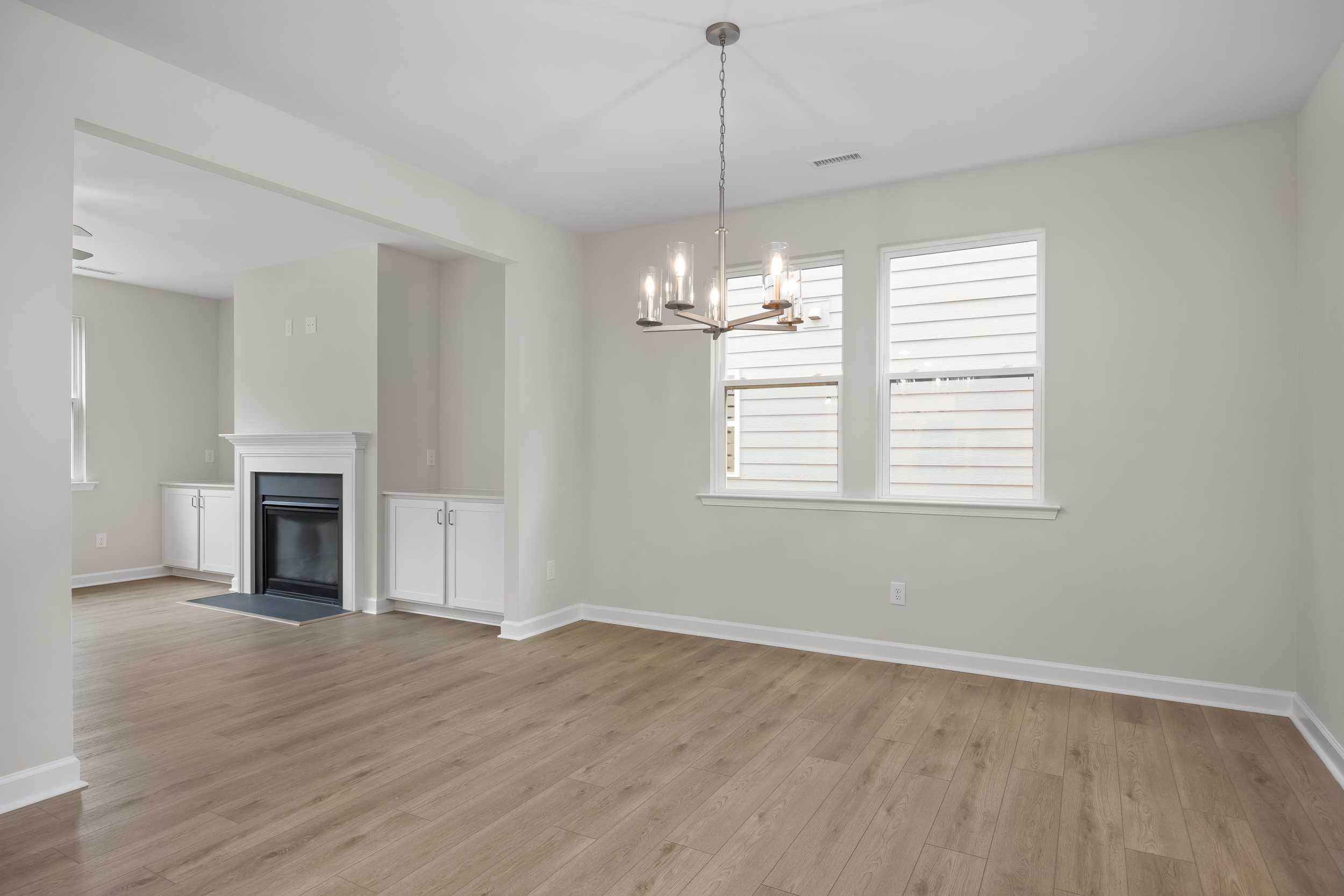 Spacious Beech C living room by Davidson Homes featuring gas fireplace, hardwood floors, chandelier, and large windows