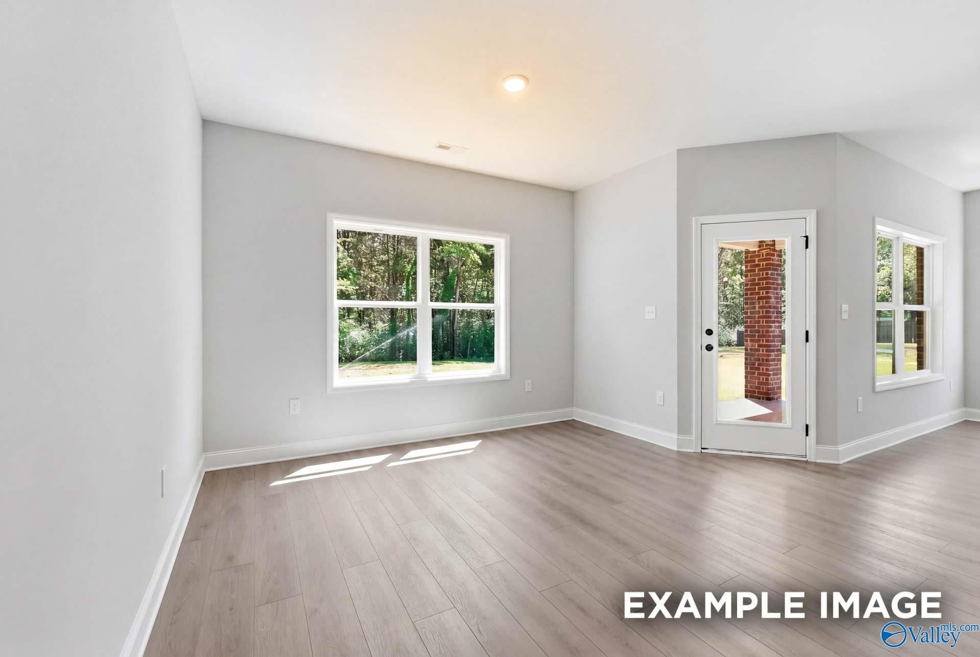 Bright living area with wood-look flooring and patio access in The Franklin C floor plan at The Meadows in Athens, AL.