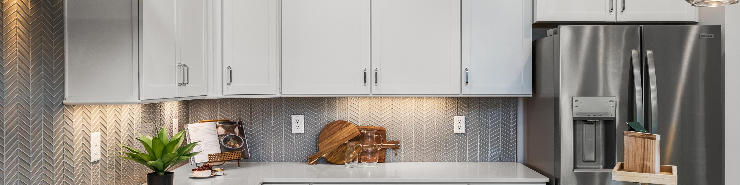 Modern white kitchen at Long Creek Townhomes in Charlotte NC with shaker cabinets, quartz island, stainless appliances, herringbone backsplash