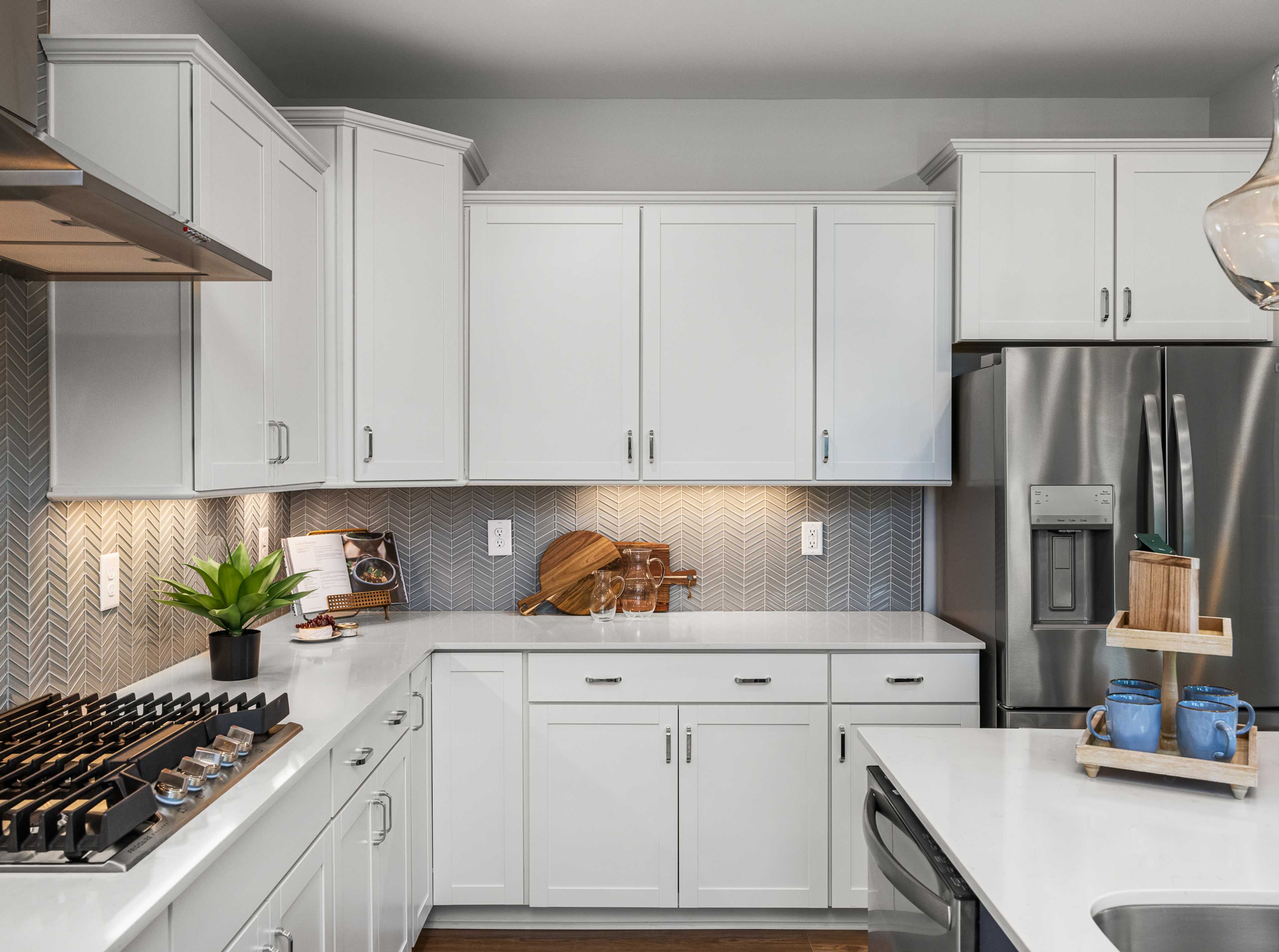 Modern white kitchen at Long Creek Townhomes in Charlotte NC with shaker cabinets, quartz island, stainless appliances, herringbone backsplash