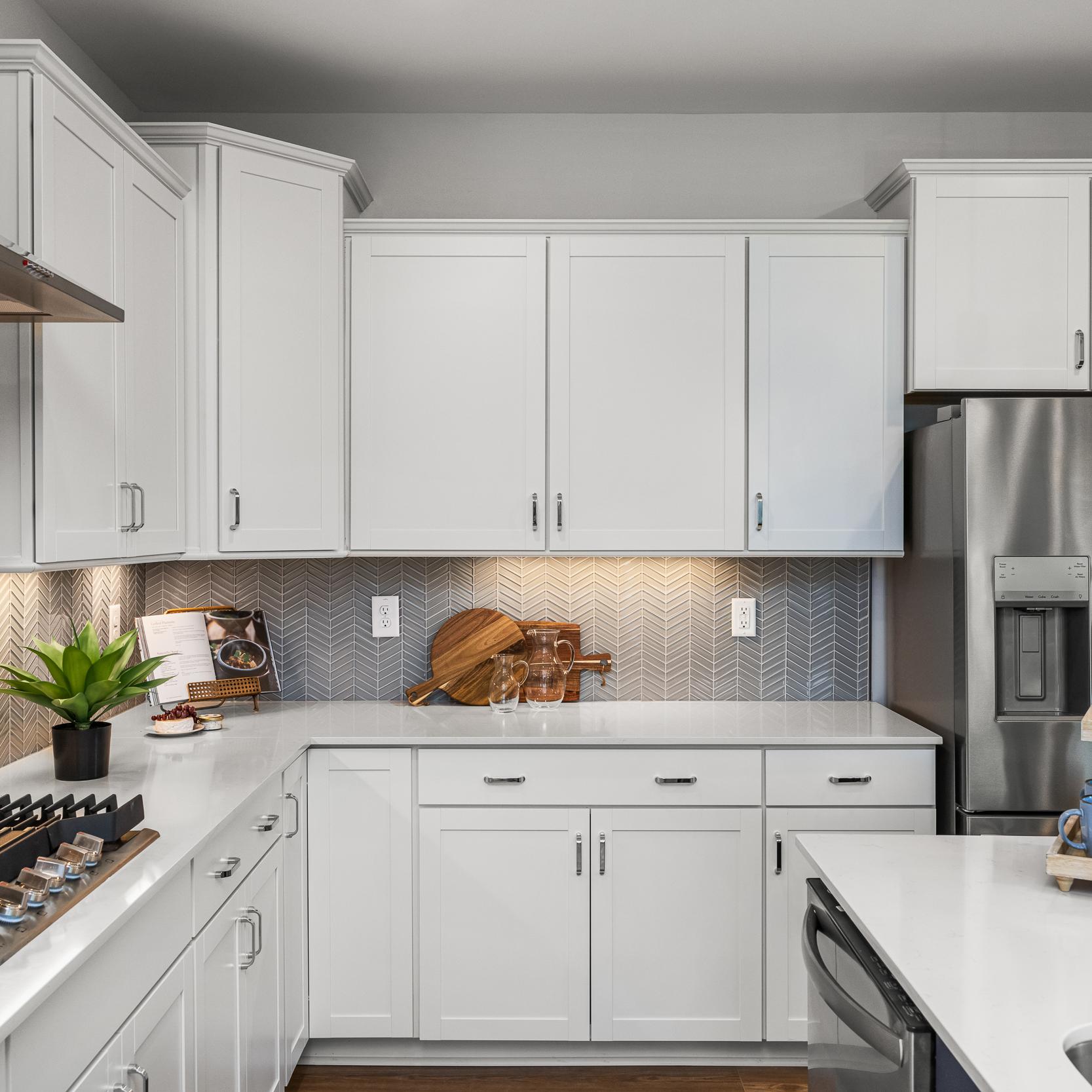 Modern white kitchen at Long Creek Townhomes in Charlotte NC with shaker cabinets, quartz island, stainless appliances, herringbone backsplash