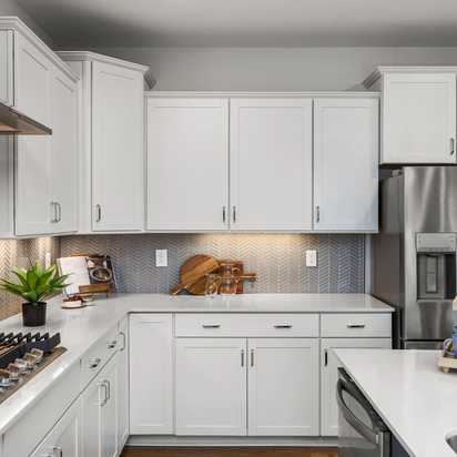 Modern white kitchen at Long Creek Townhomes in Charlotte NC with shaker cabinets, quartz island, stainless appliances, herringbone backsplash