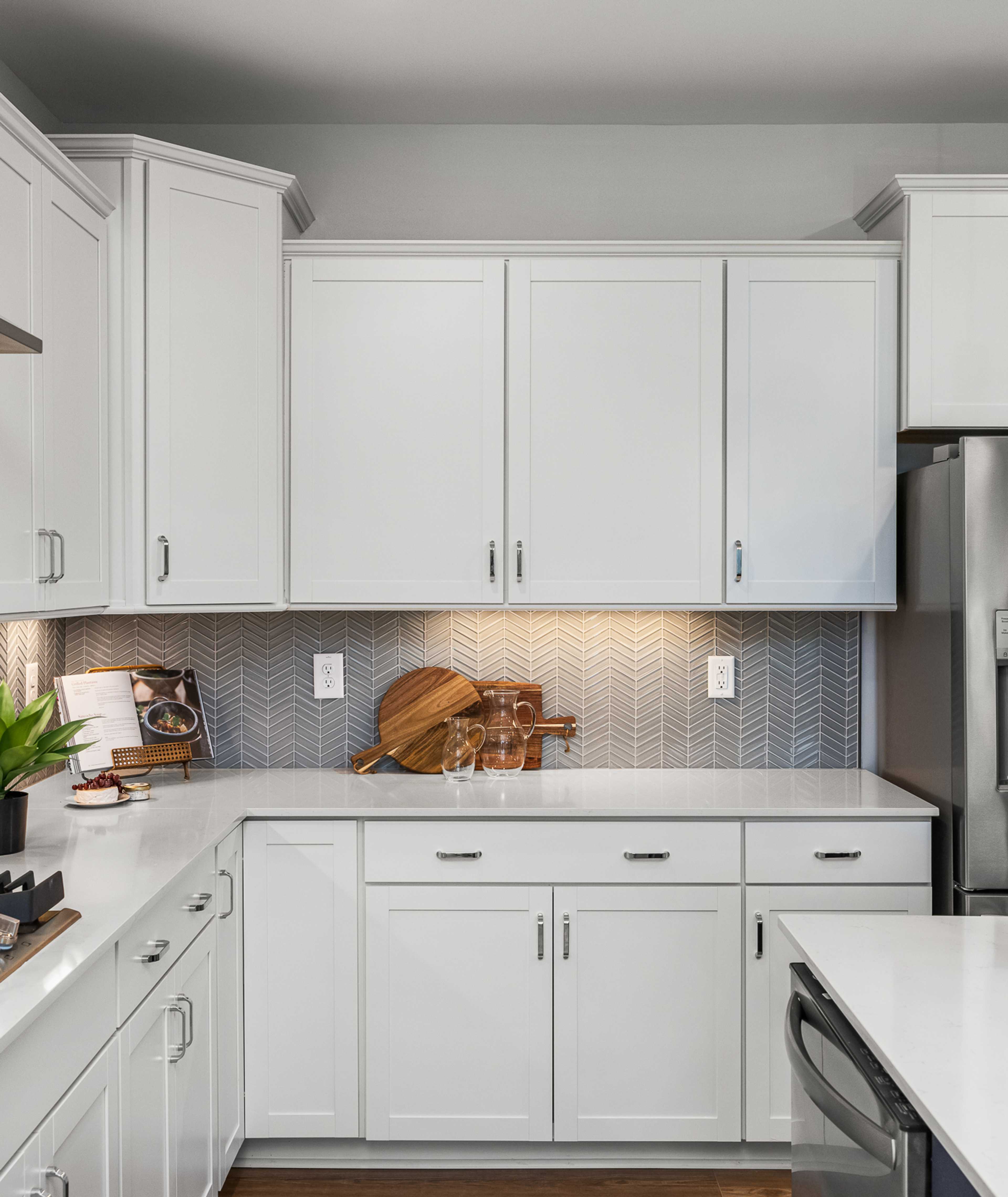 Modern white kitchen at Long Creek Townhomes in Charlotte NC with shaker cabinets, quartz island, stainless appliances, herringbone backsplash