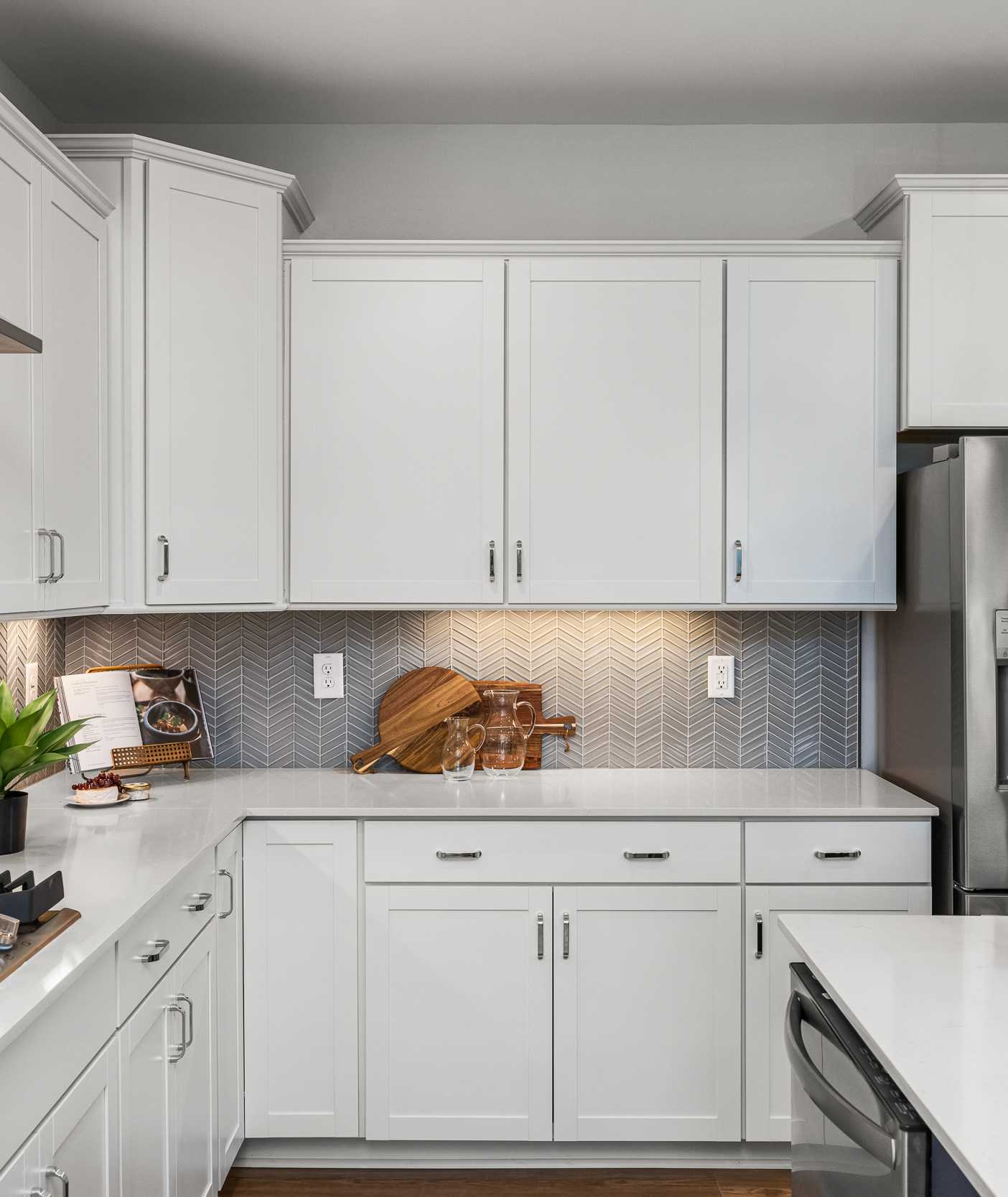 Modern white kitchen at Long Creek Townhomes in Charlotte NC with shaker cabinets, quartz island, stainless appliances, herringbone backsplash