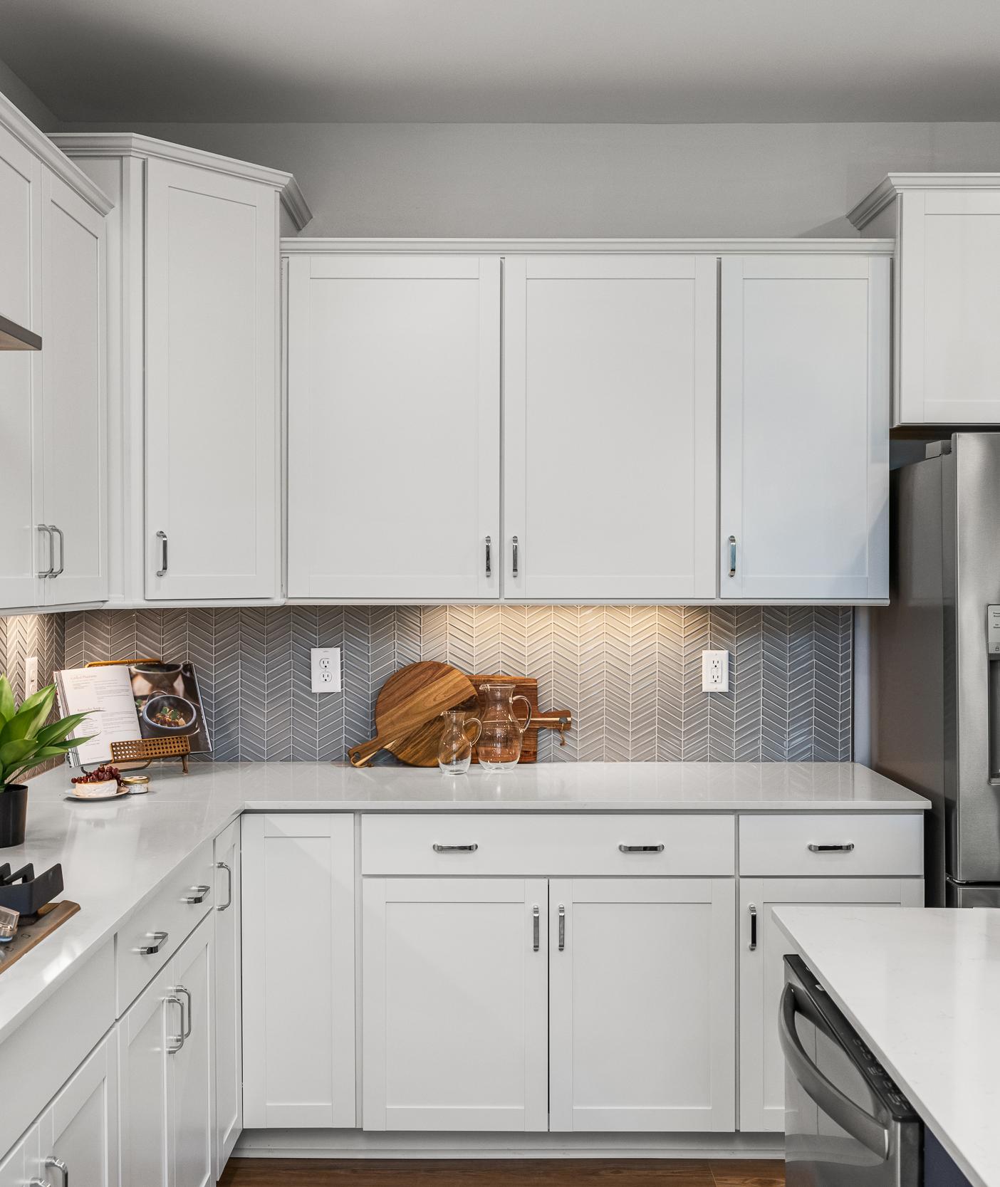 Modern white kitchen at Long Creek Townhomes in Charlotte NC with shaker cabinets, quartz island, stainless appliances, herringbone backsplash