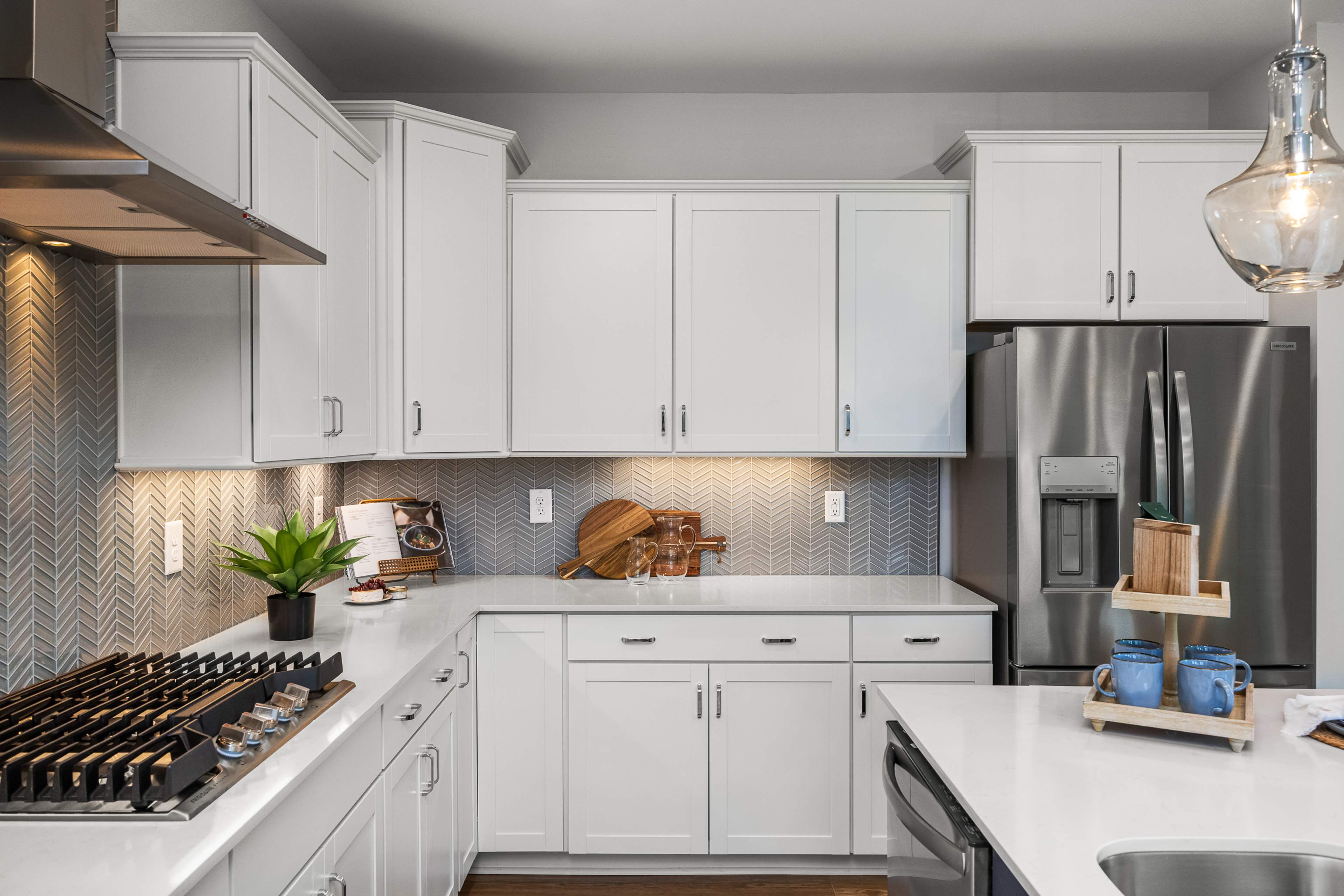 Modern white kitchen at Long Creek Townhomes in Charlotte NC with shaker cabinets, quartz island, stainless appliances, herringbone backsplash