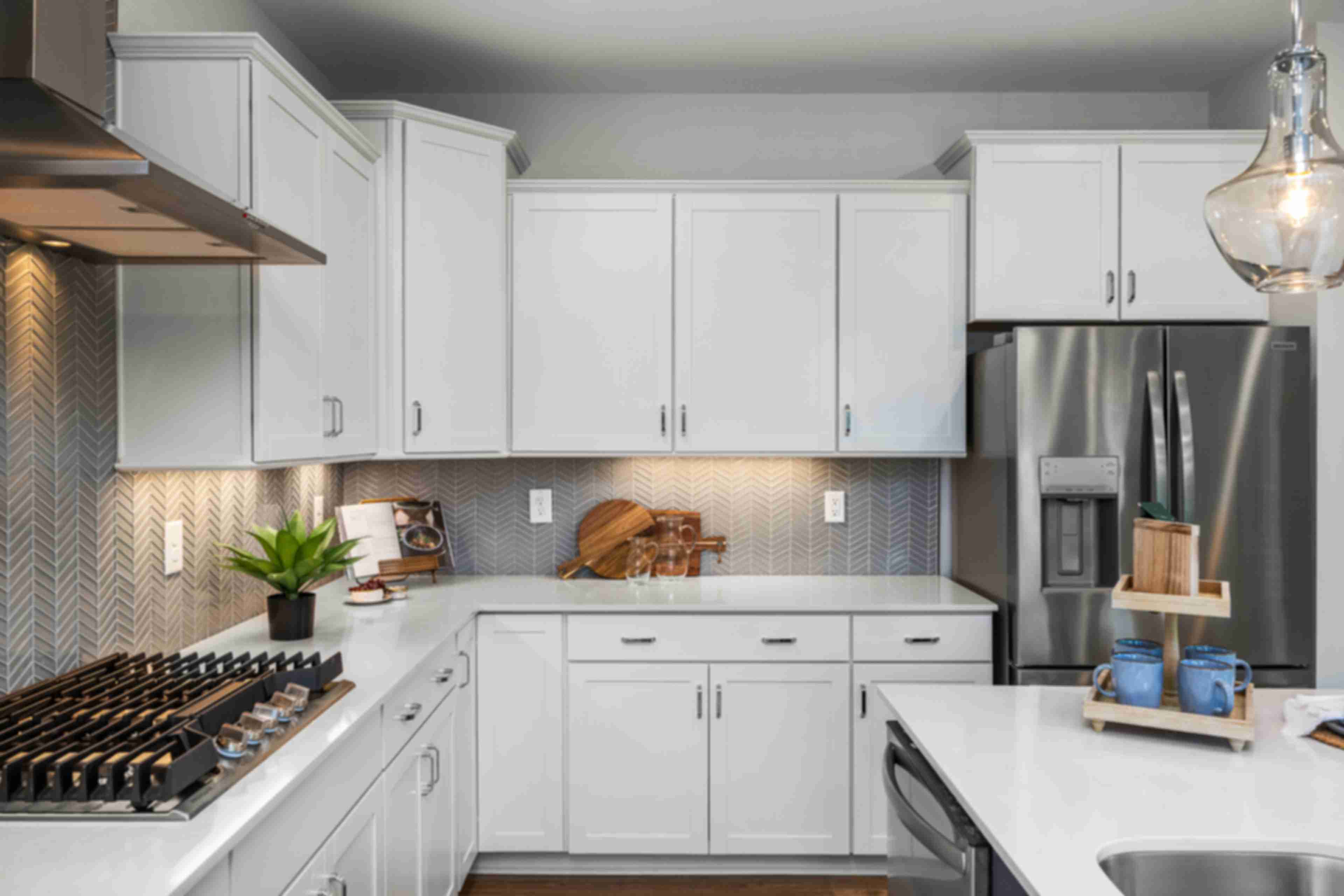 Modern white kitchen at Long Creek Townhomes in Charlotte NC with shaker cabinets, quartz island, stainless appliances, herringbone backsplash