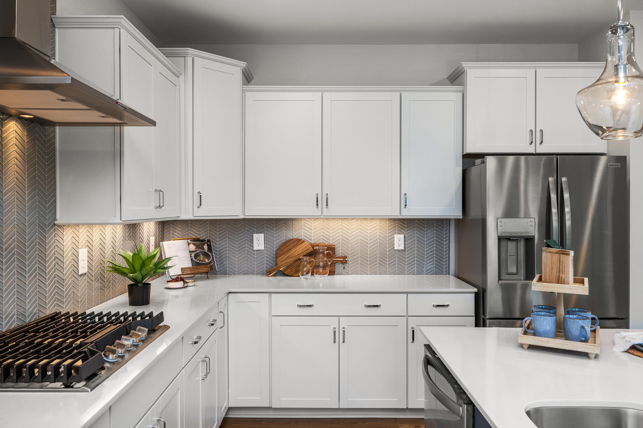 Modern white kitchen at Long Creek Townhomes in Charlotte NC with shaker cabinets, quartz island, stainless appliances, herringbone backsplash