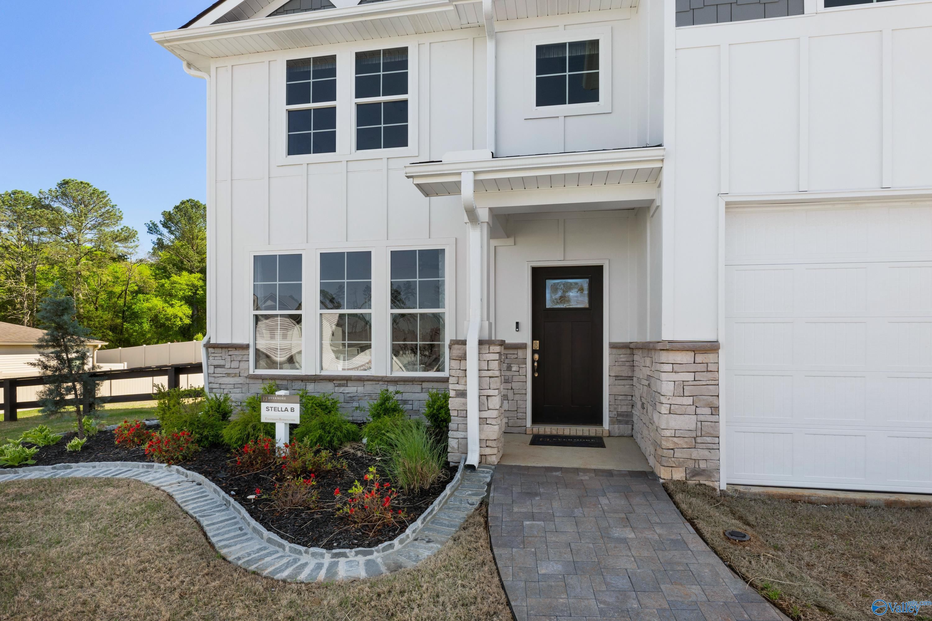 Two-story white Davidson Homes Stella with stone accents, covered porch, 2-car garage, and landscaped yard in Evergreen Mill, Madison, AL