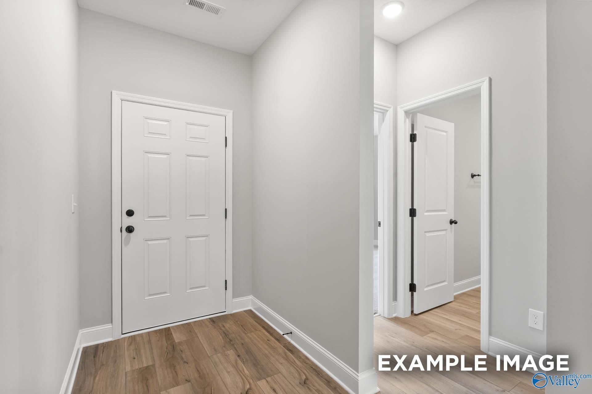 Bright hallway featuring white paneled doors and hardwood floors in The Asheville C 3-bedroom home by Davidson Homes, Hazel Green, Alabama