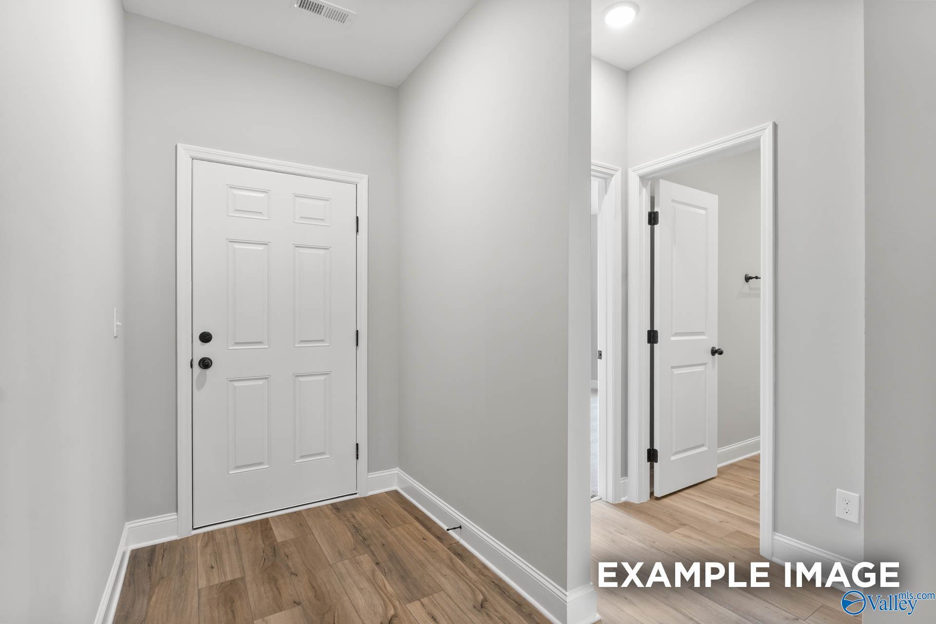 Bright hallway featuring white paneled doors and hardwood floors in The Asheville C 3-bedroom home by Davidson Homes, Hazel Green, Alabama