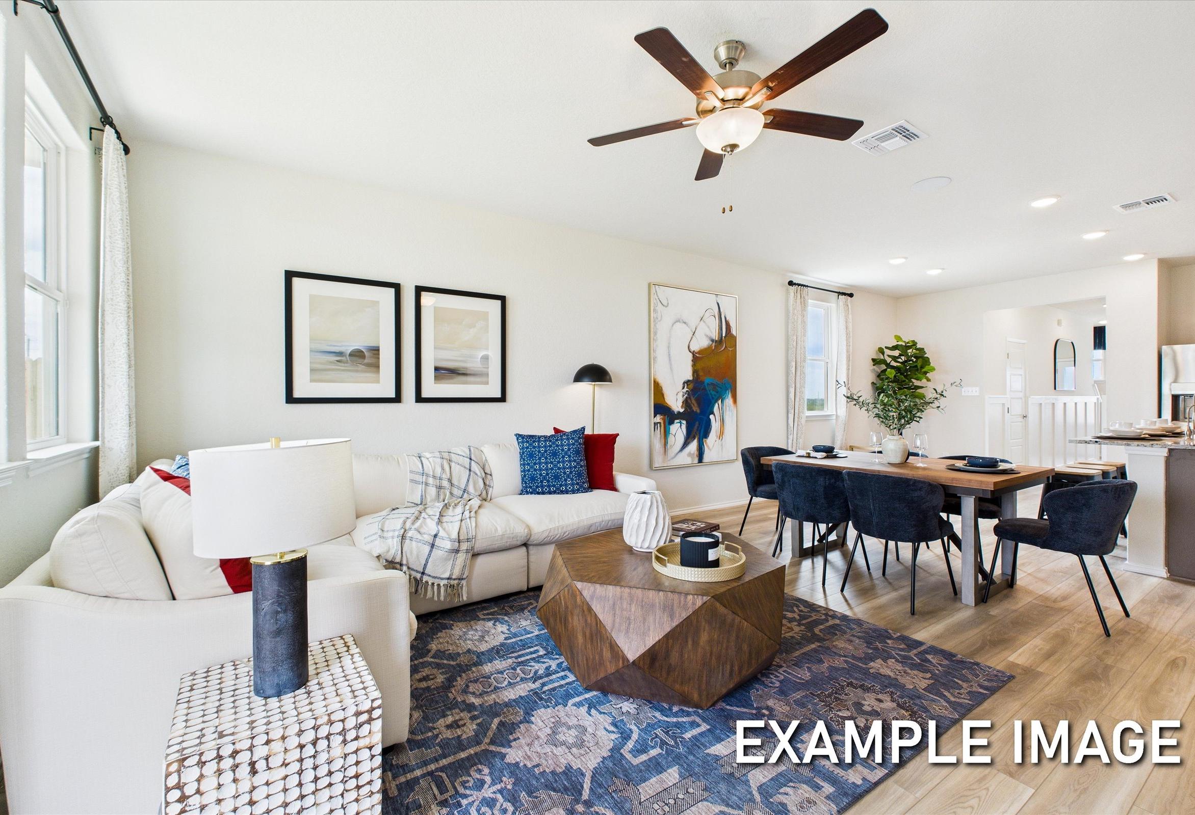 Spacious open-concept living room in The Brazos A with L-shaped white sofa, dining table, ceiling fan, and modern artwork