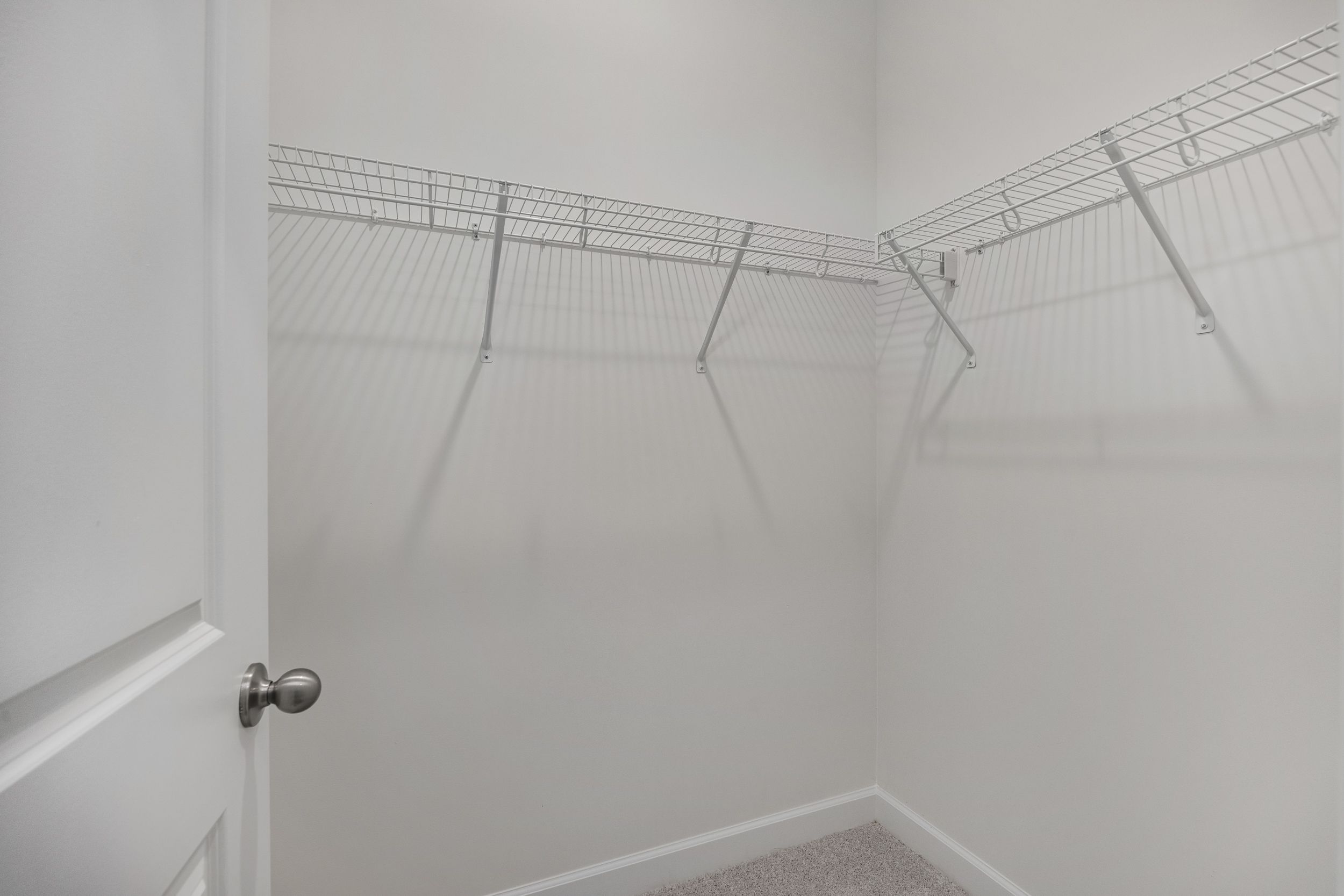 Spacious walk-in closet in The Aspen C master suite with white wire shelving and open storage walls