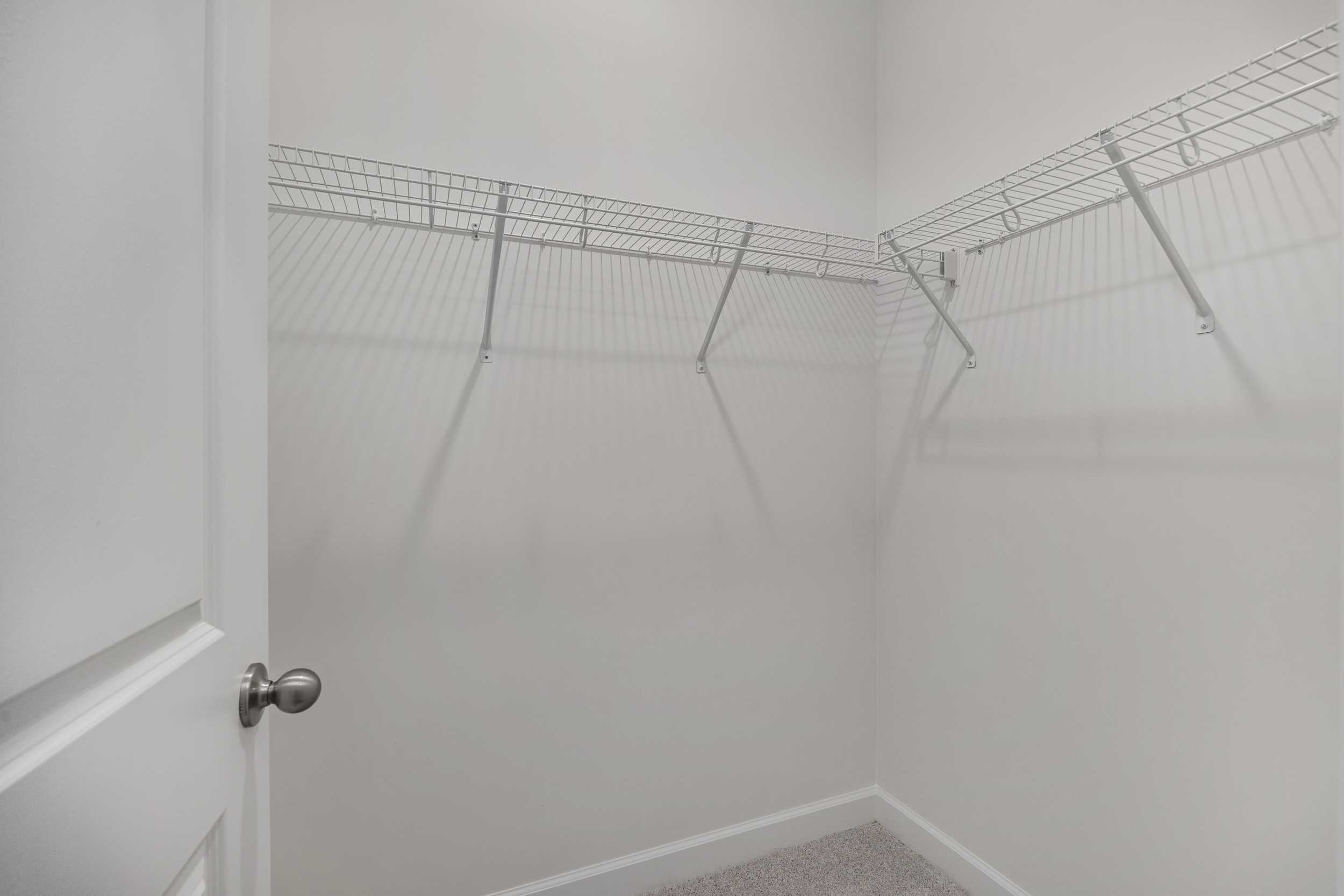 Spacious walk-in closet in The Aspen C master suite with white wire shelving and open storage walls
