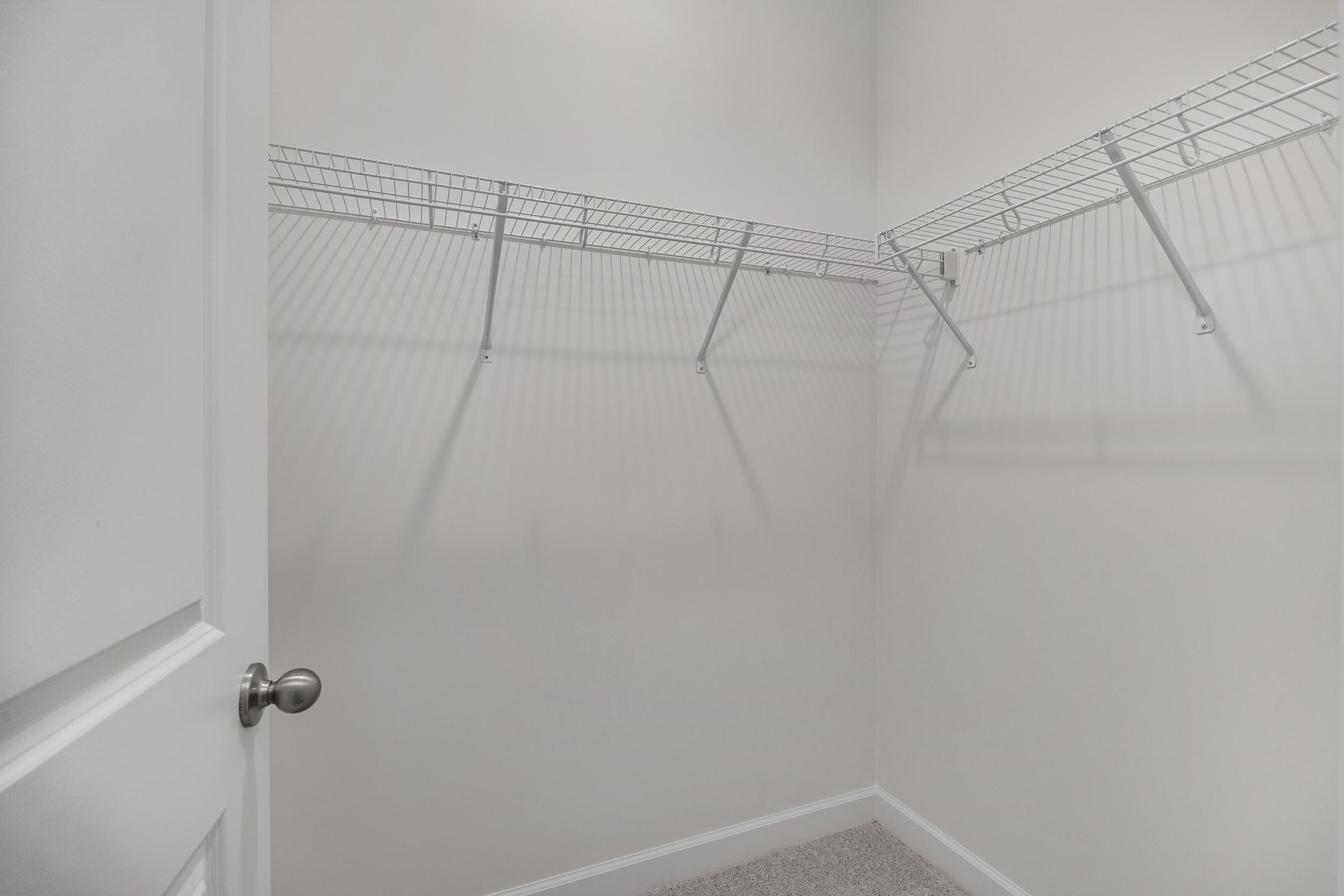 Spacious walk-in closet in The Aspen C master suite with white wire shelving and open storage walls