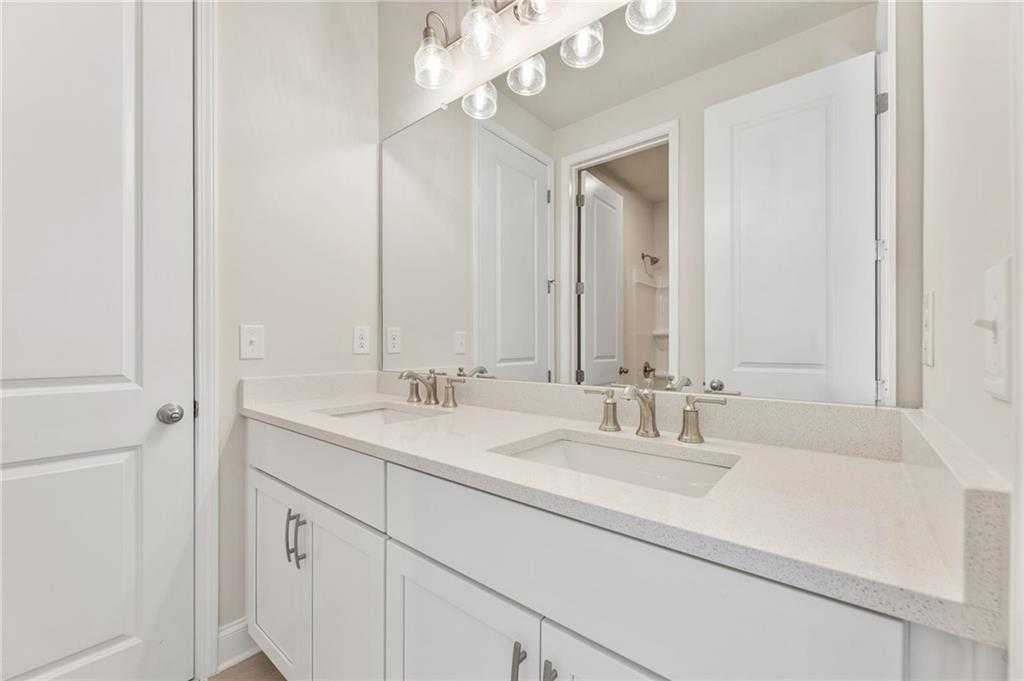 Elegant double vanity bathroom with white shaker cabinets, quartz counters, dual sinks, and frameless mirror in The Danbury E, Buford, GA