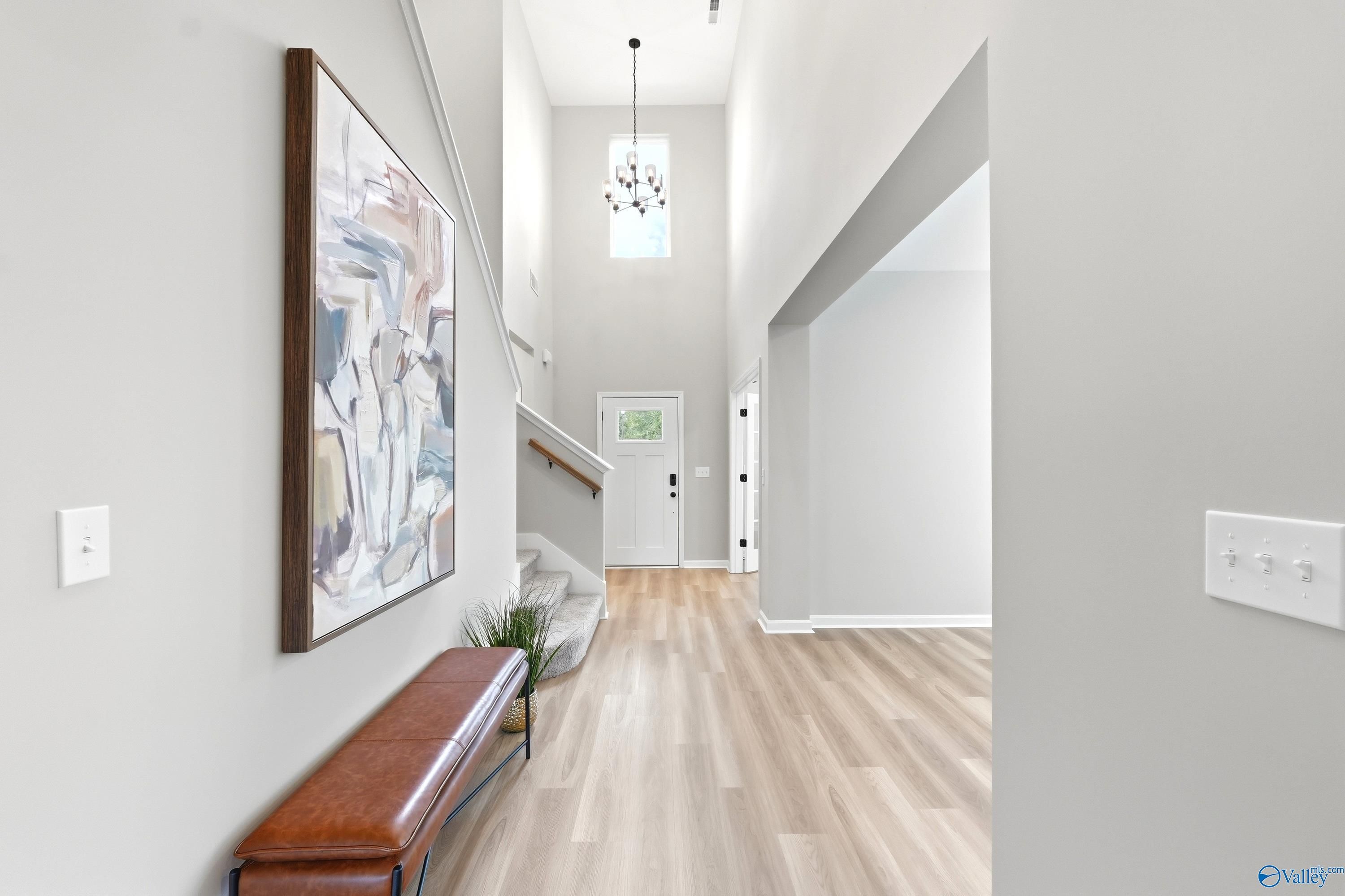 Two-story foyer with high ceilings, modern chandelier, and wood flooring in The Dorado floor plan, Riverton Preserve.