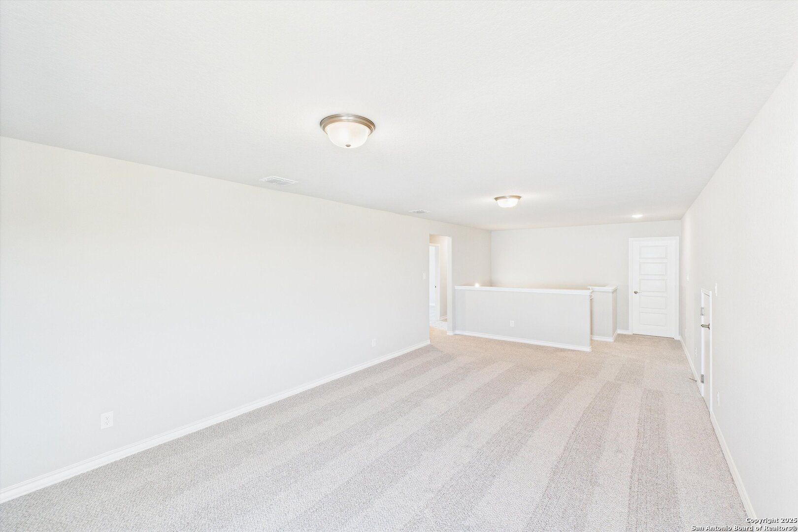 Spacious upstairs loft with light gray carpet, white walls, recessed lighting in The Jennings H floor plan, Ladera, San Antonio