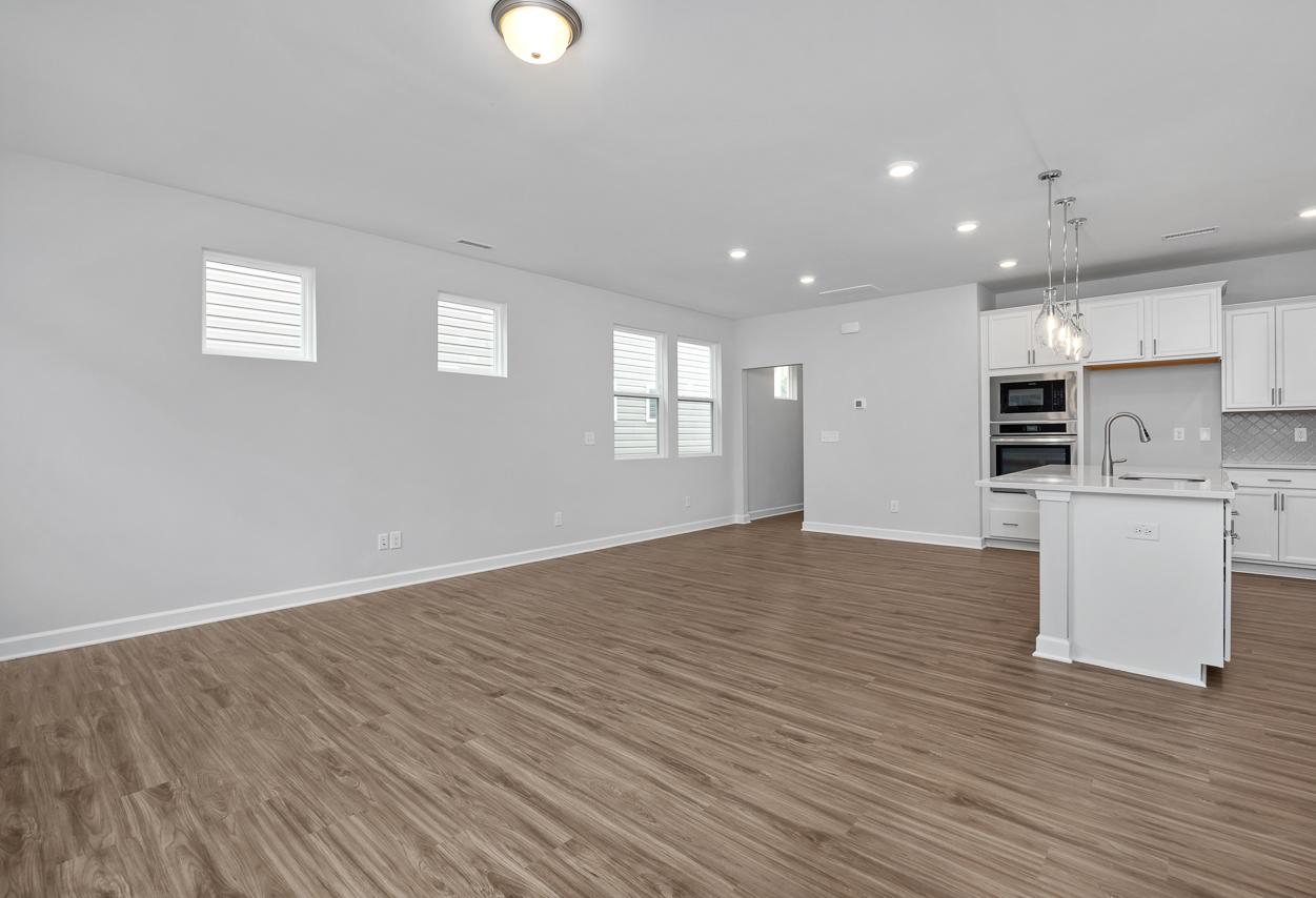 Spacious open-concept kitchen in The Durham C by Davidson Homes featuring white cabinetry, large island, and hardwood floors