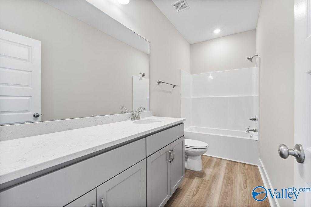 Modern master bathroom featuring double vanity with quartz countertop, tub-shower combo, and subway tile in Evermore Homes The Oxford, Owens Cross Roads, AL
