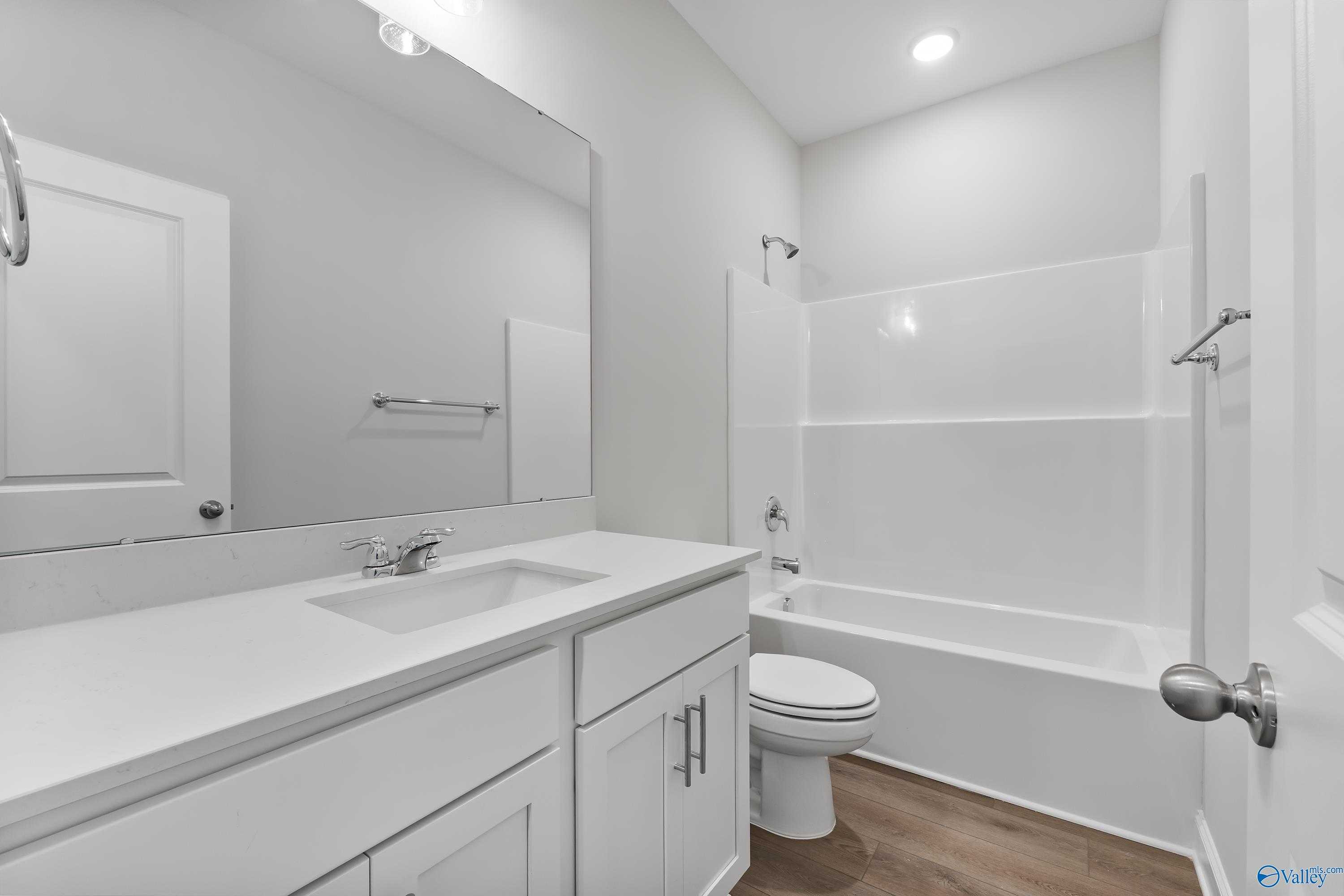 Modern guest bathroom featuring white vanity, tub-shower combo, and neutral tones in Davidson Homes The Daphne, Hazel Green, AL